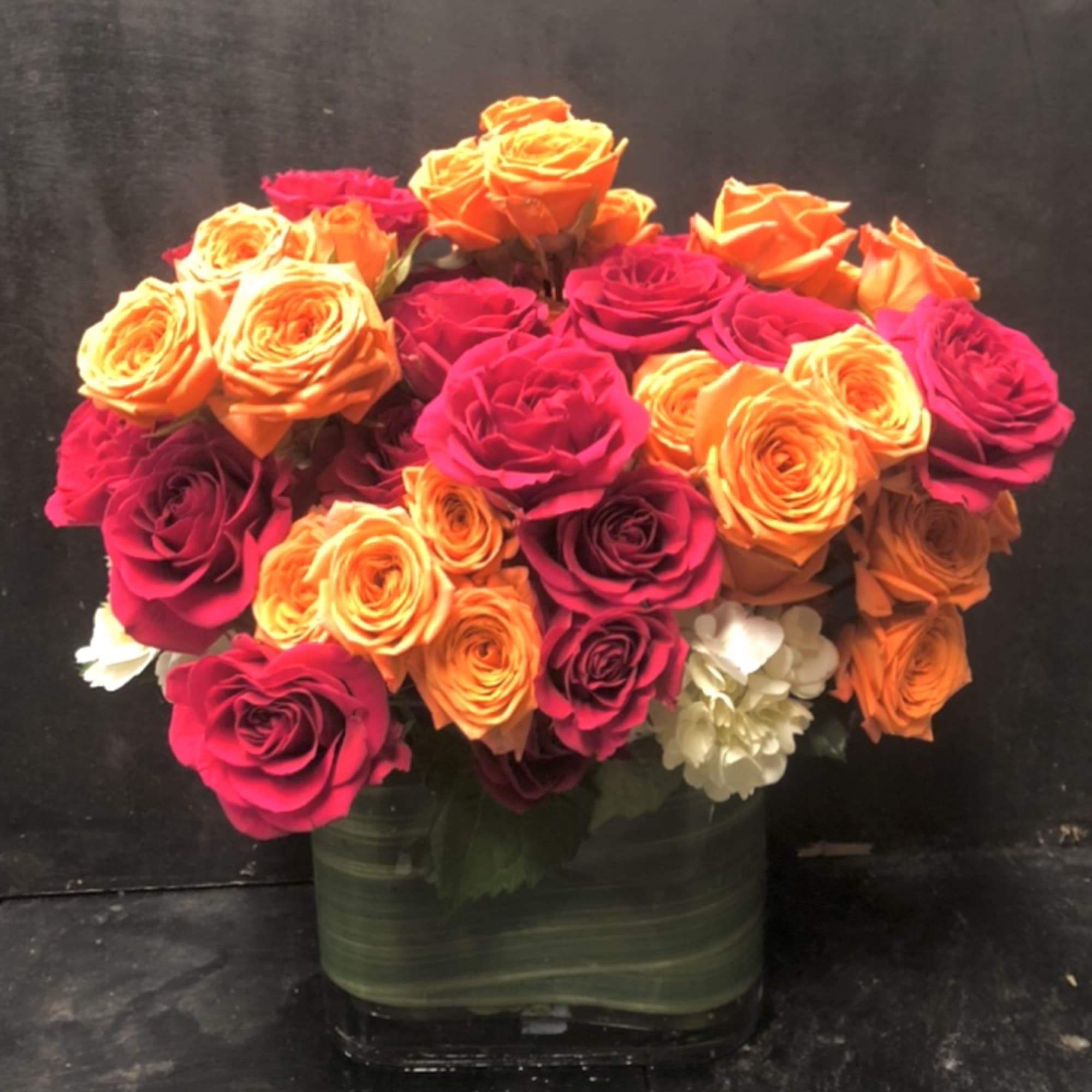 Bouquet of orange and hot pink roses in a glass vase