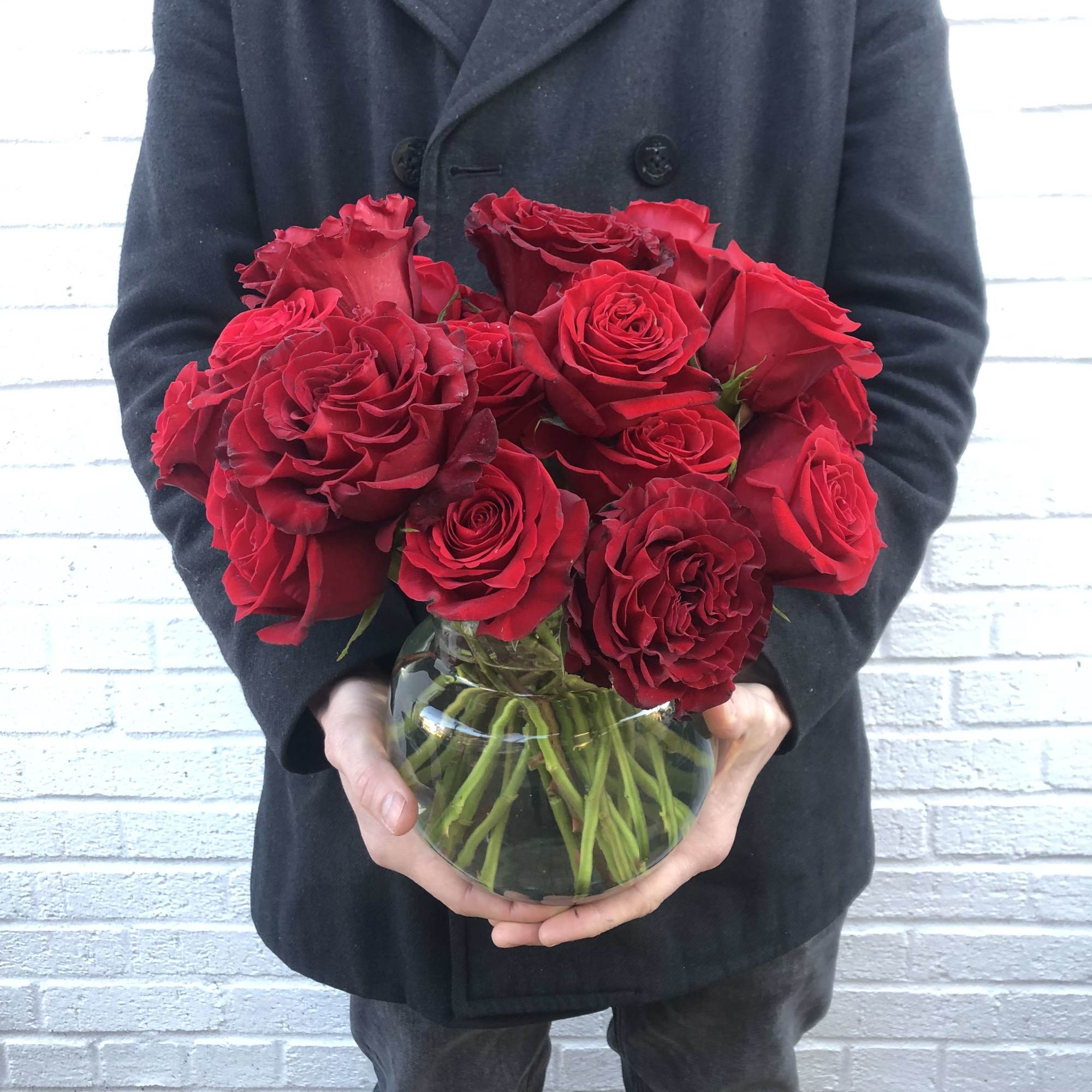 Red roses arranged in a round glass vase