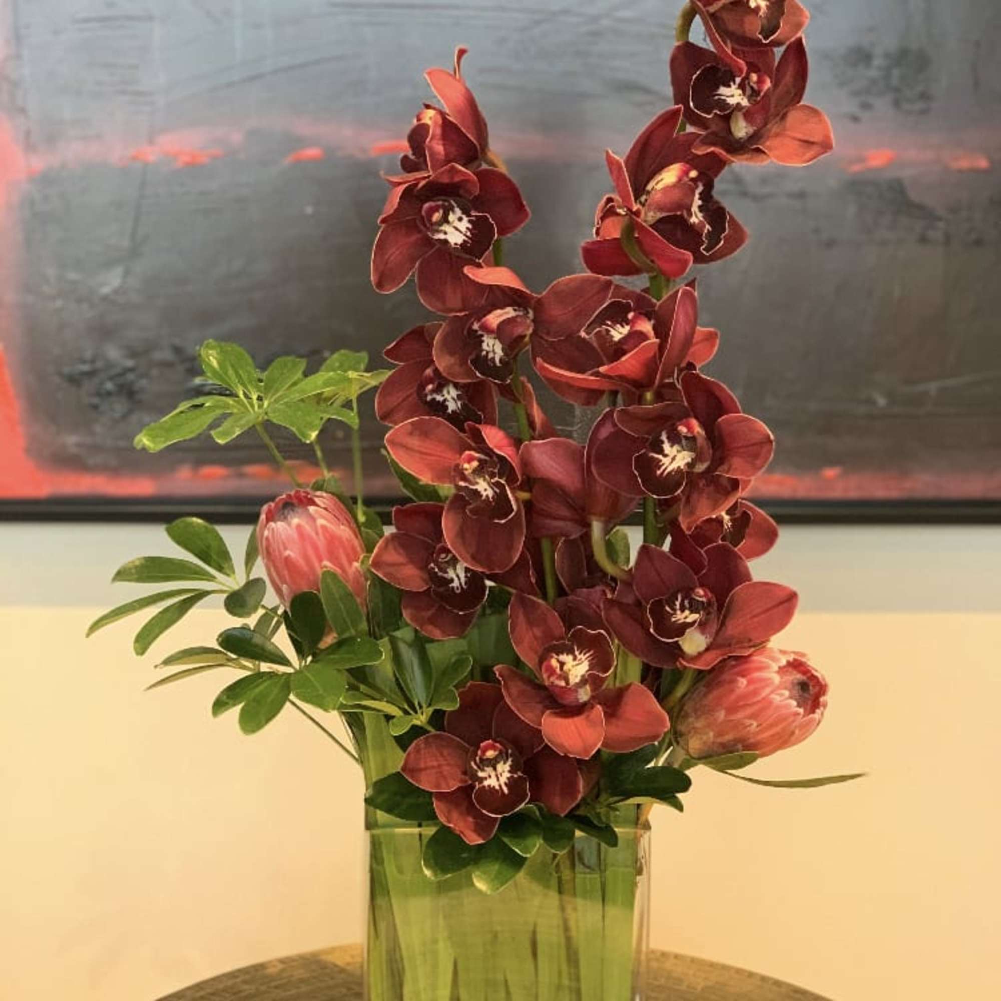 Red orchid arrangement in a clear rectangular vase