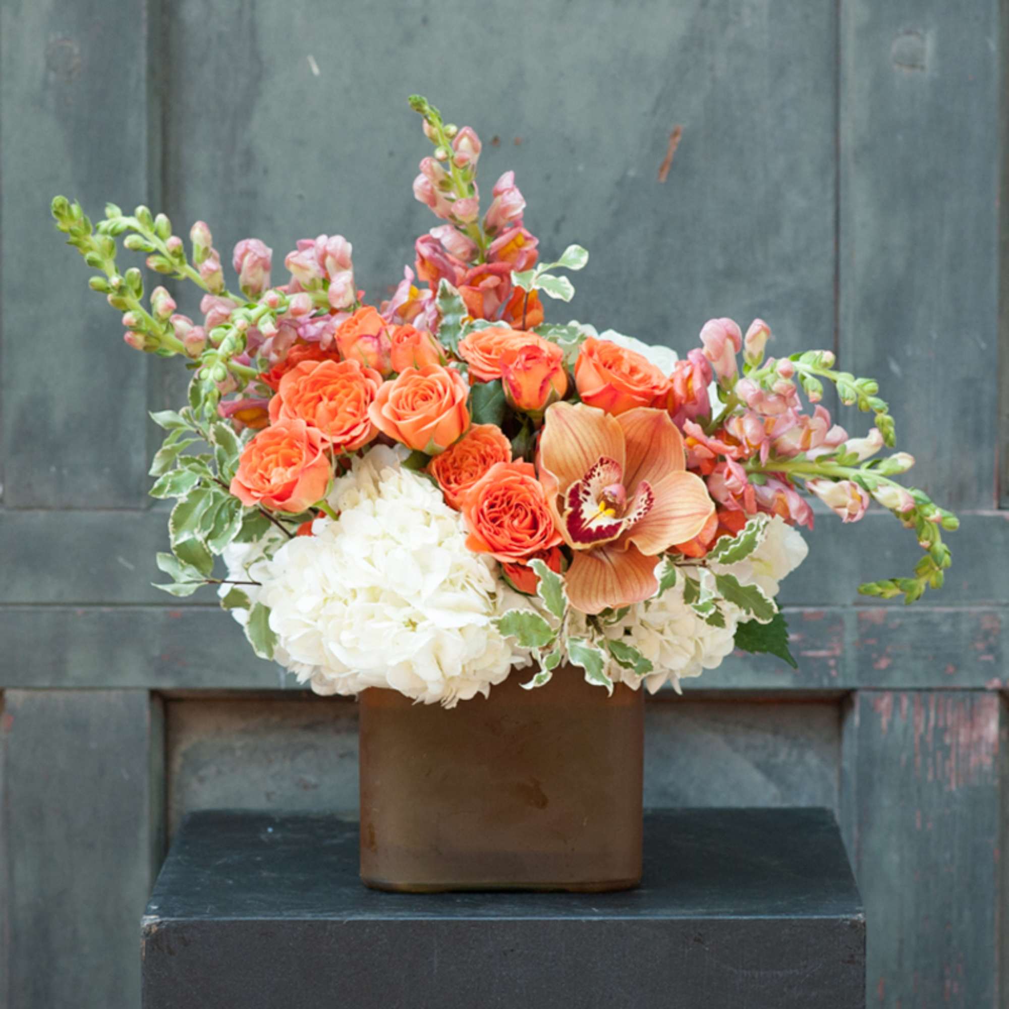 Orange roses and white hydrangeas in a brown vase