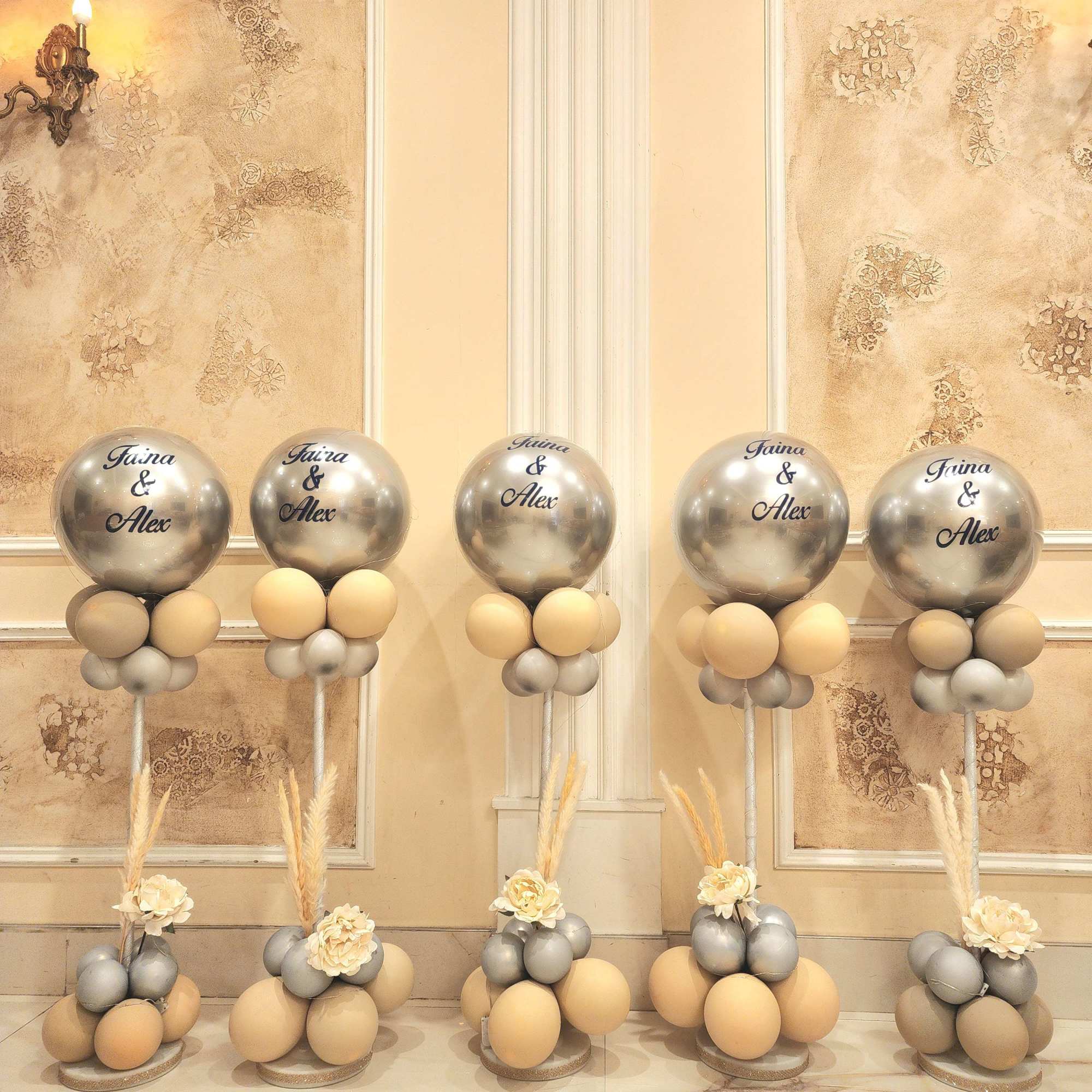 Silver and beige balloon arrangements with small cream flowers and dried grass