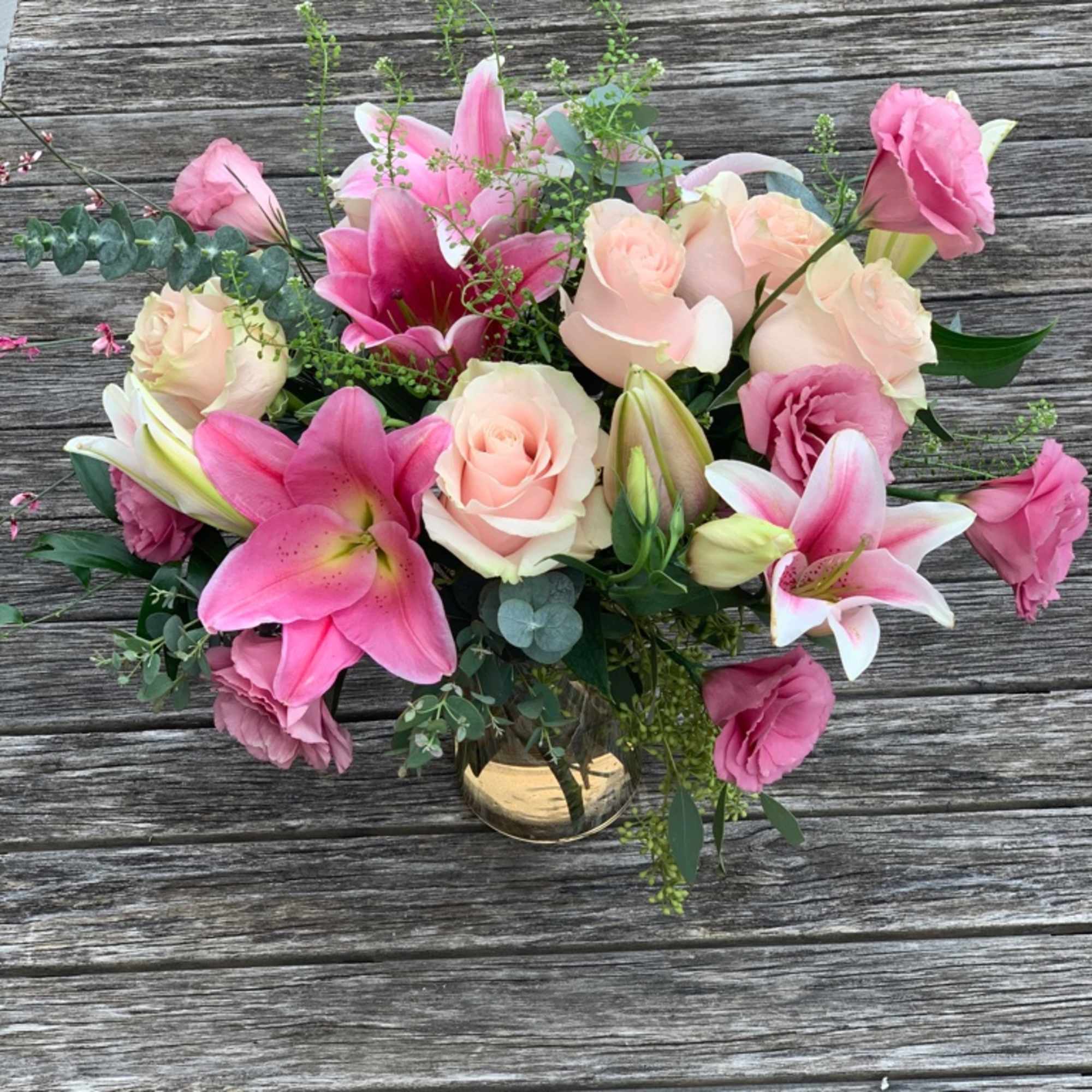 Pink lilies and roses arranged in a glass vase