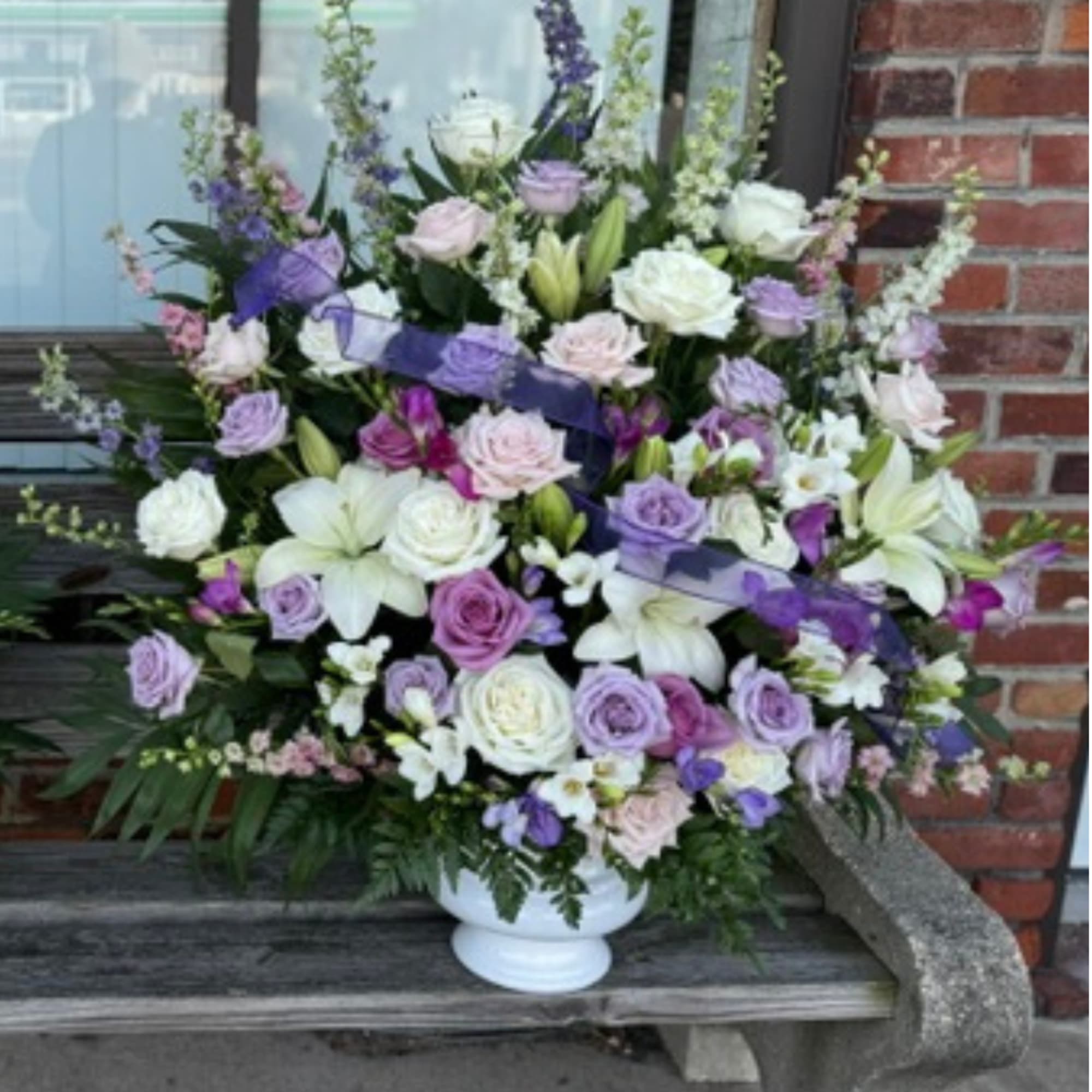 Purple and white arrangement to be displayed at funeral service. Vase arrangement