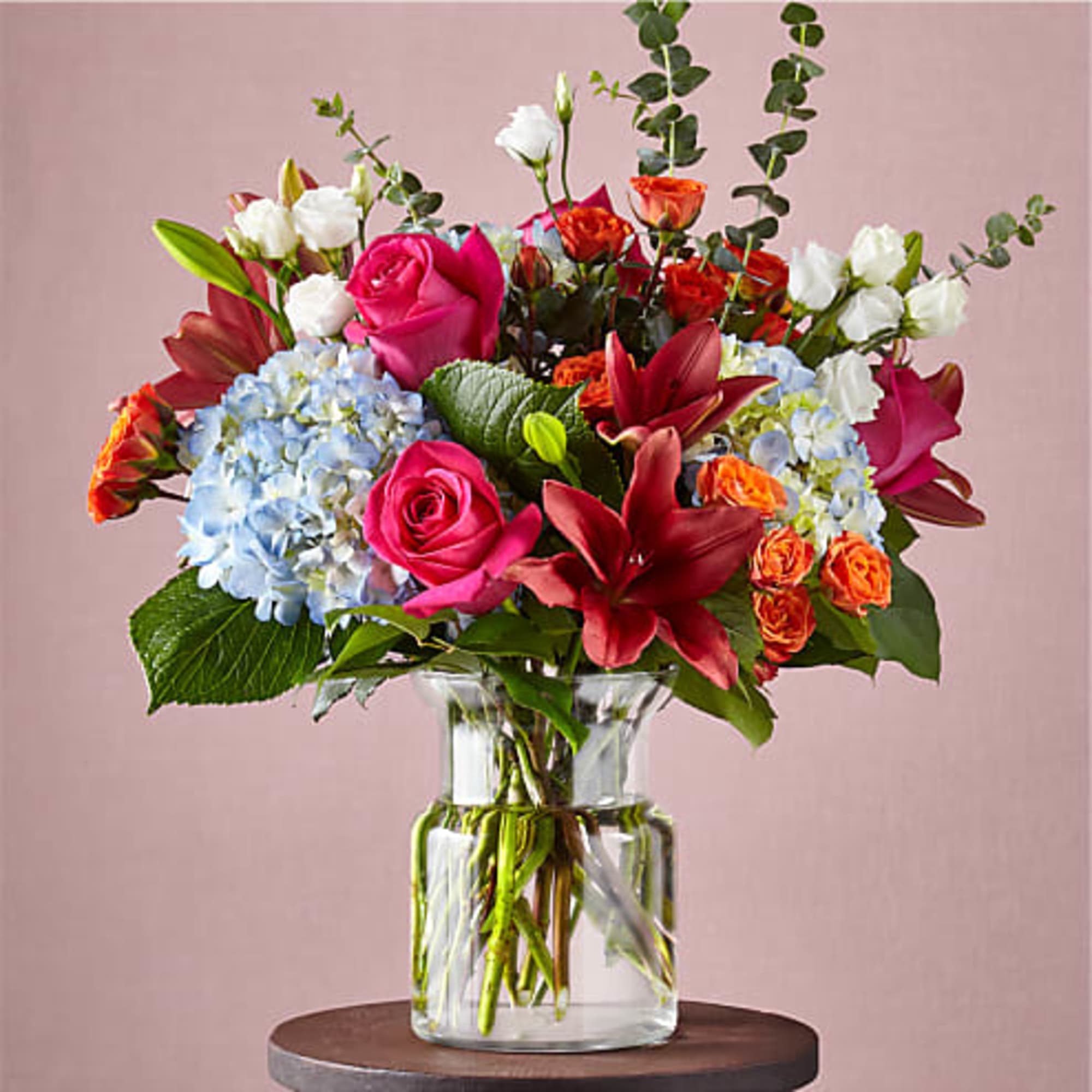 Mixed bouquet of roses, lilies, and hydrangeas in a clear glass vase, photo 2 of 3