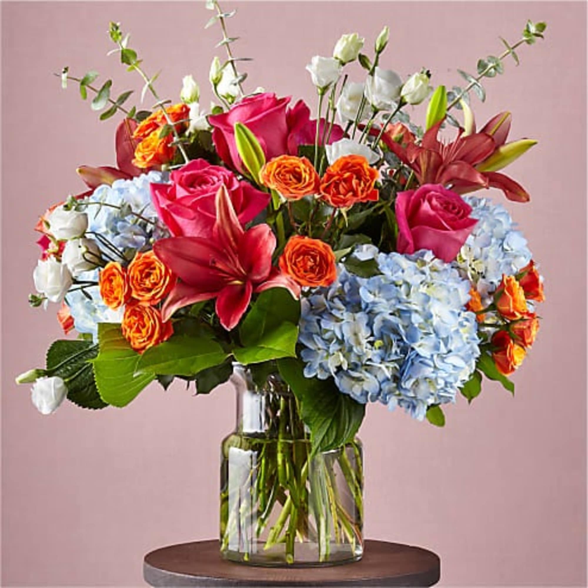Mixed bouquet of roses, lilies, and hydrangeas in a glass vase