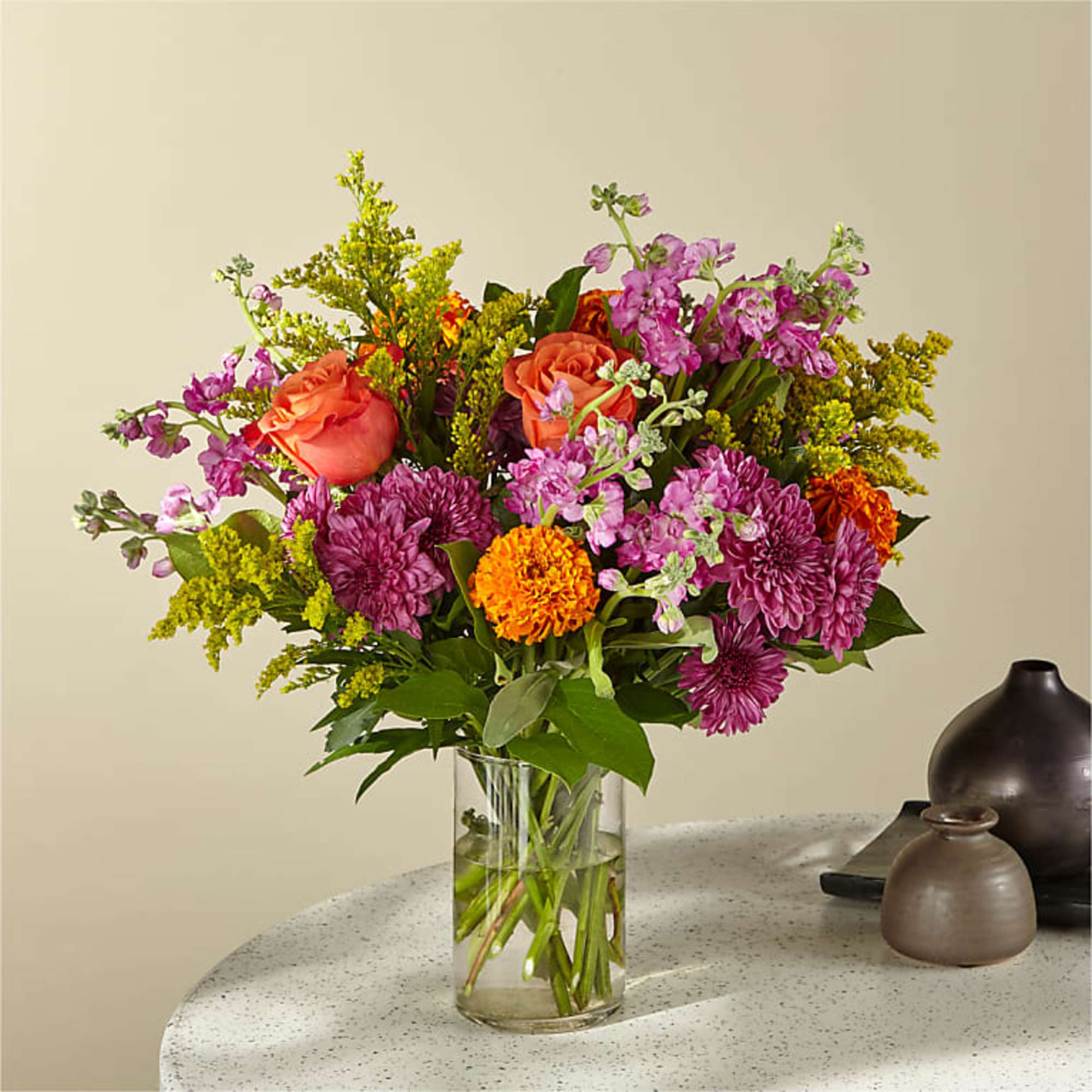 Mixed bouquet of pink, orange, and purple flowers in a clear glass vase