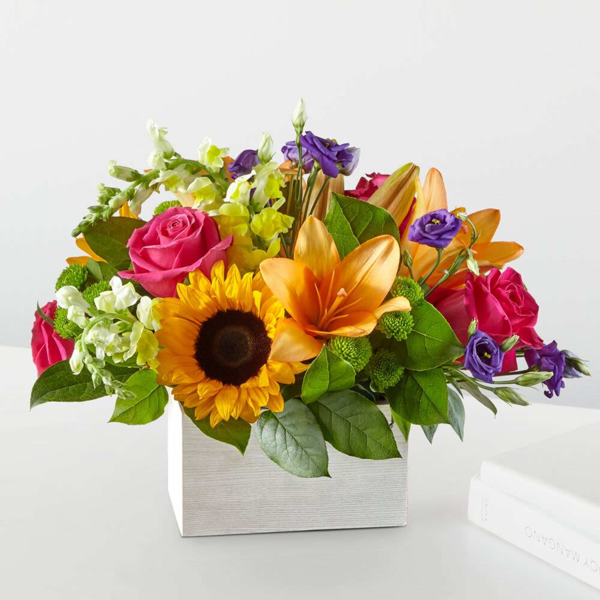 Mixed bouquet with sunflowers, roses, lilies, and purple blooms in a white box