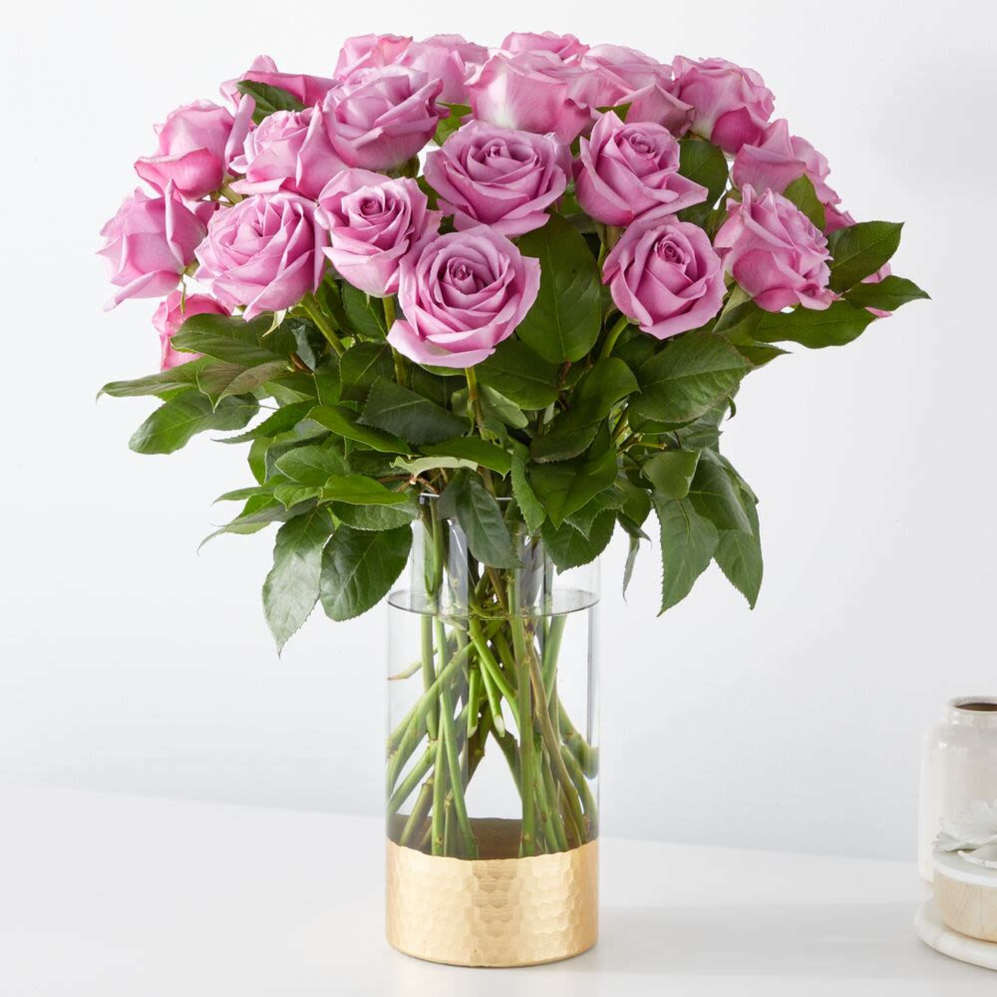 Pink roses arranged in a clear glass vase with a gold base