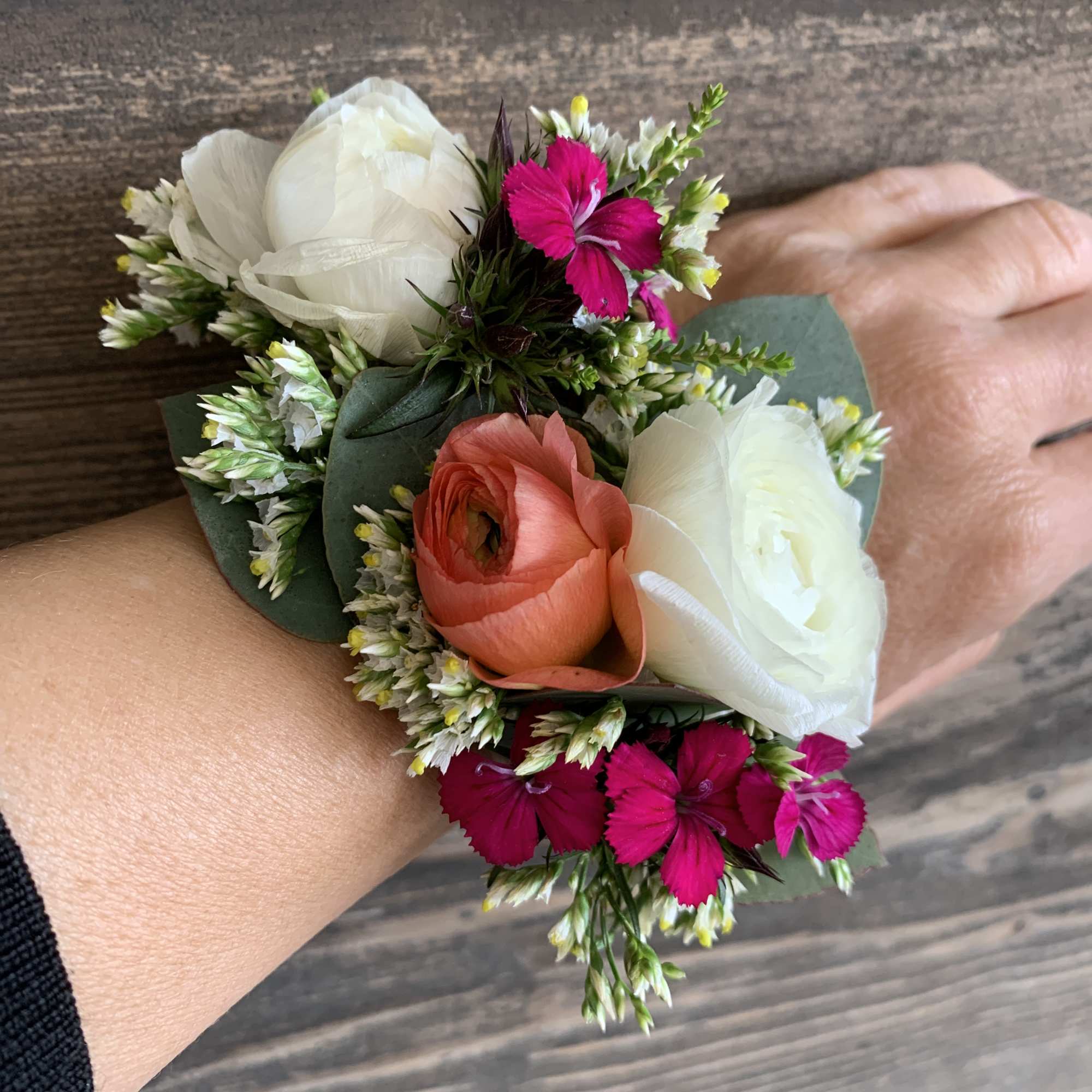 Small wrist corsage with white, coral, and bright pink flowers