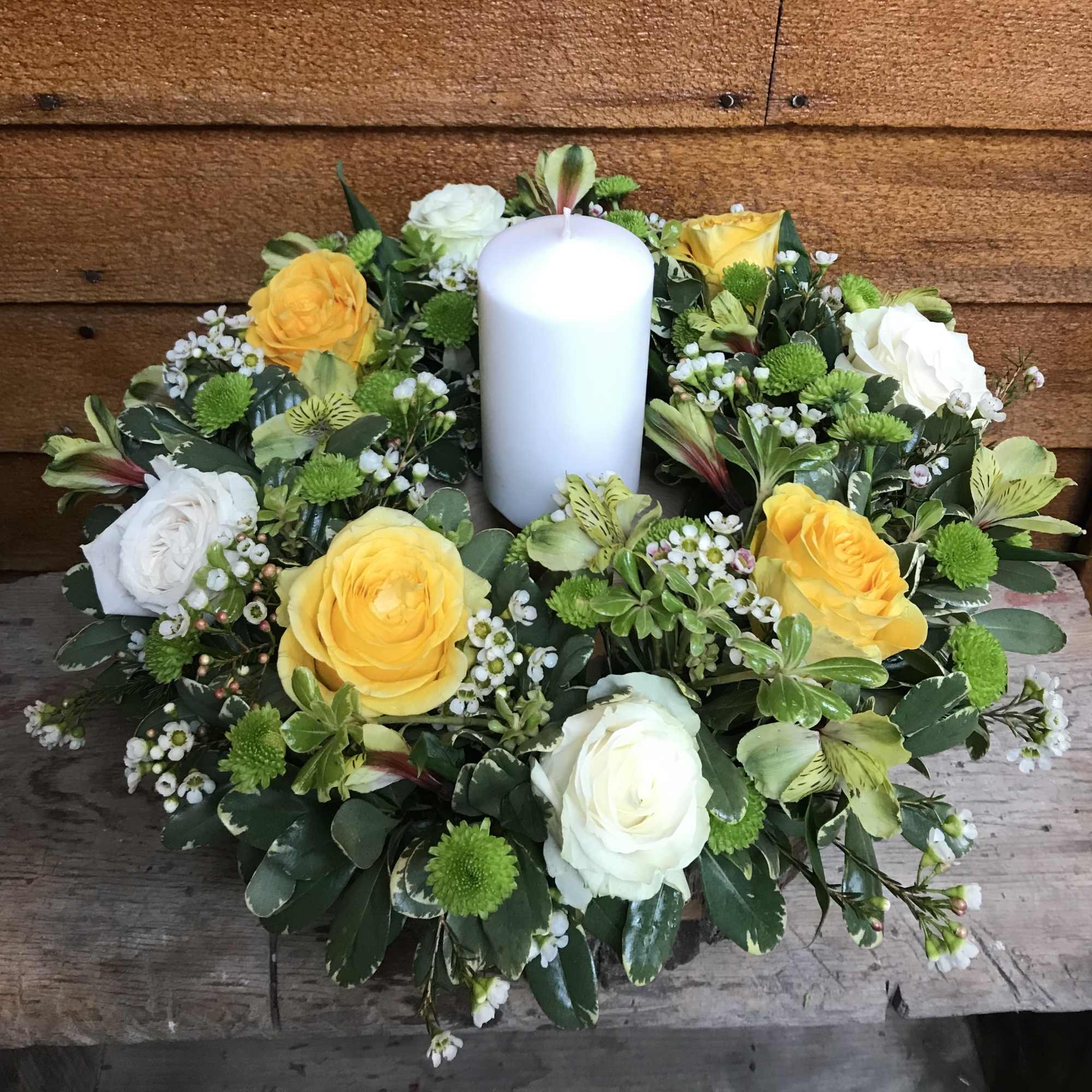 Round floral wreath with a white pillar candle in the center