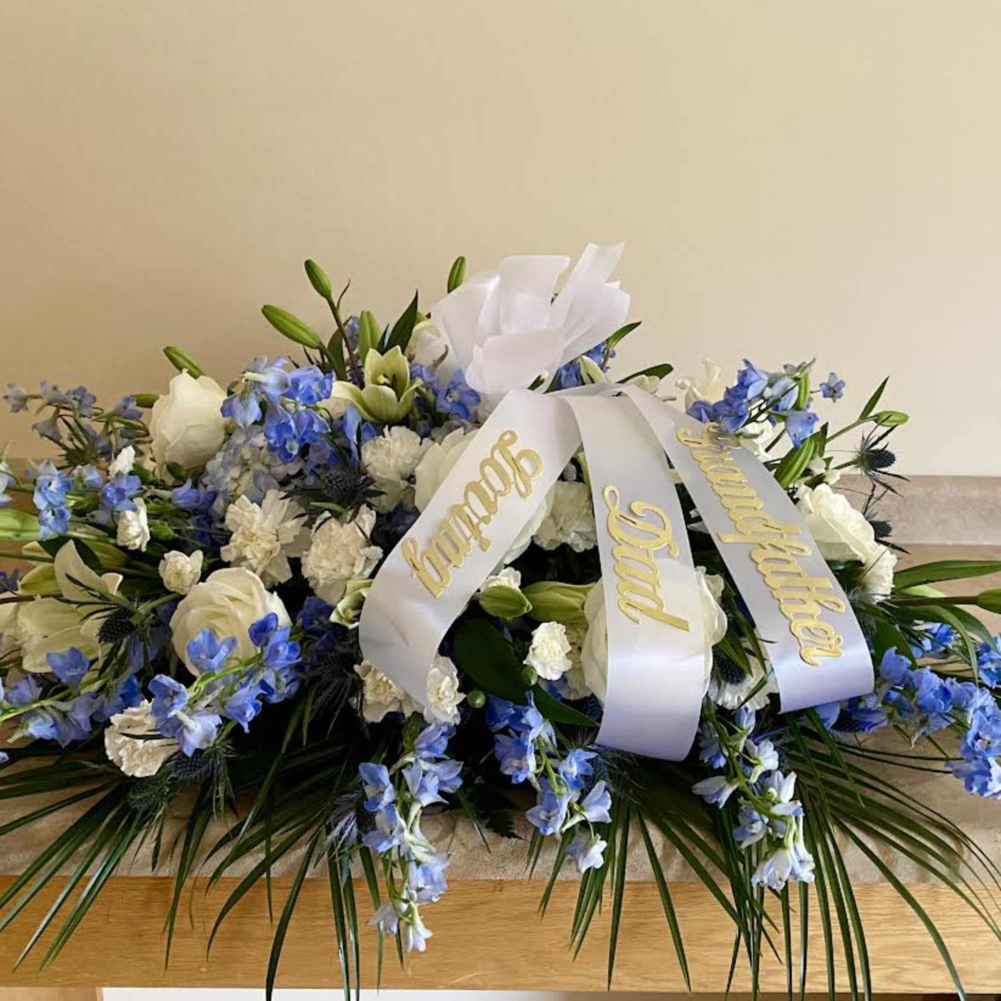 White and blue funeral spray with a memorial ribbon