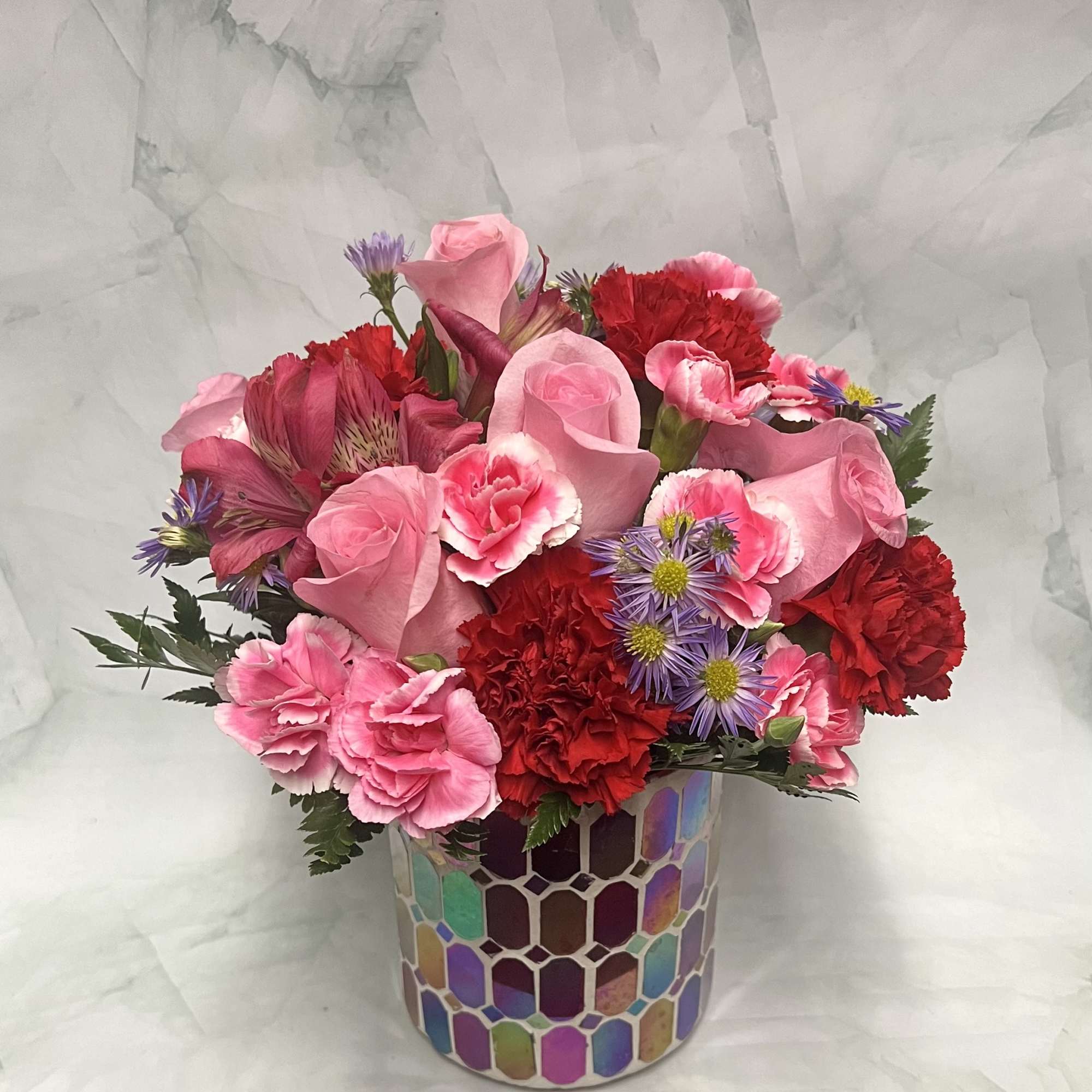 Pink and red mixed bouquet in a mosaic-patterned vase