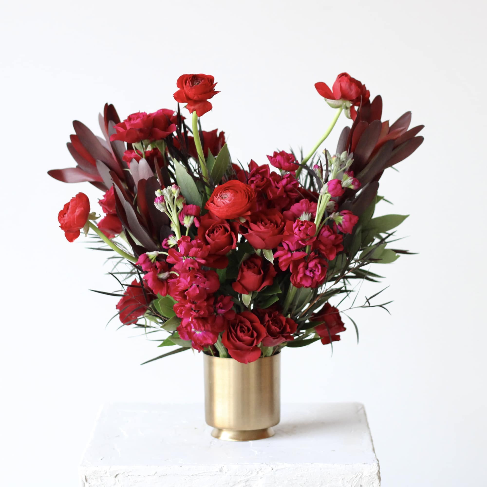 Red floral arrangement in a gold vase