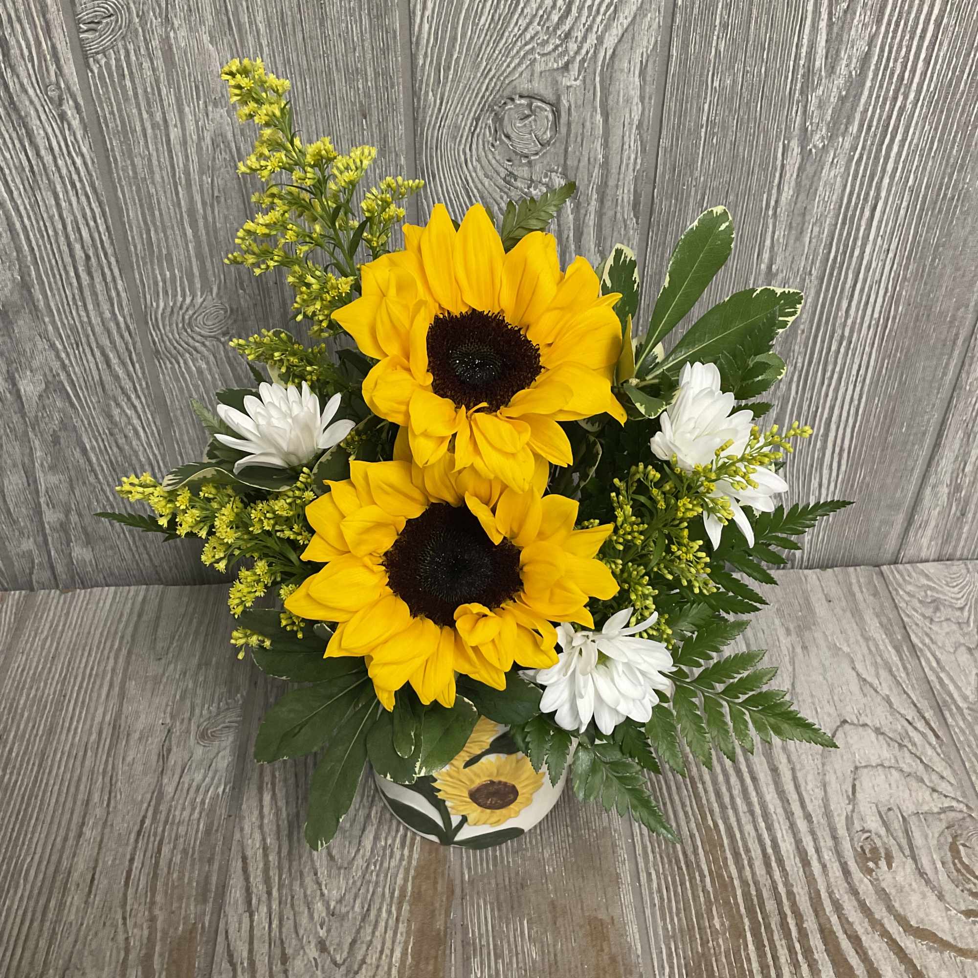 Sunflower arrangement with white daisies in a decorated pot