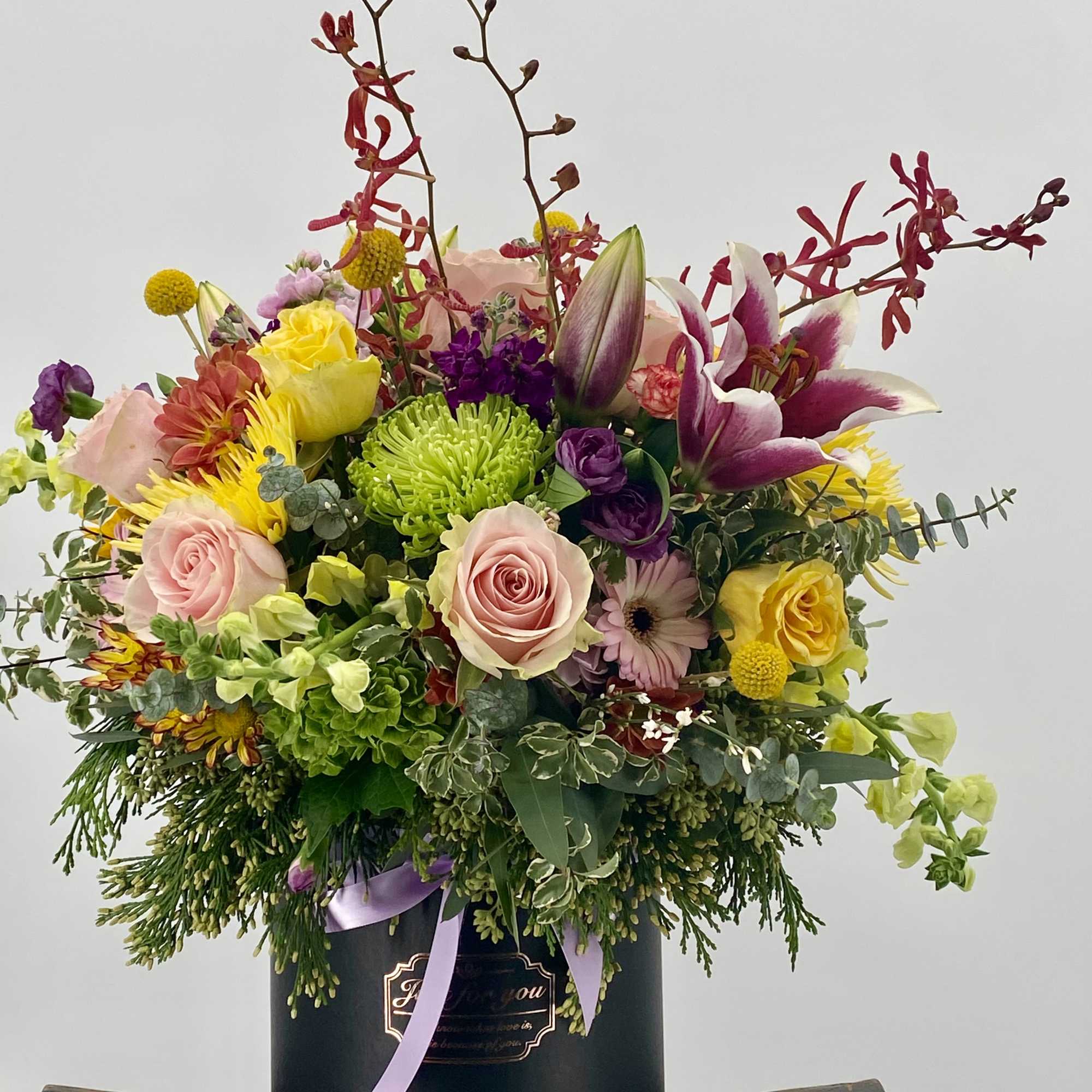 Mixed bouquet in a black hatbox with pink, yellow, and purple flowers