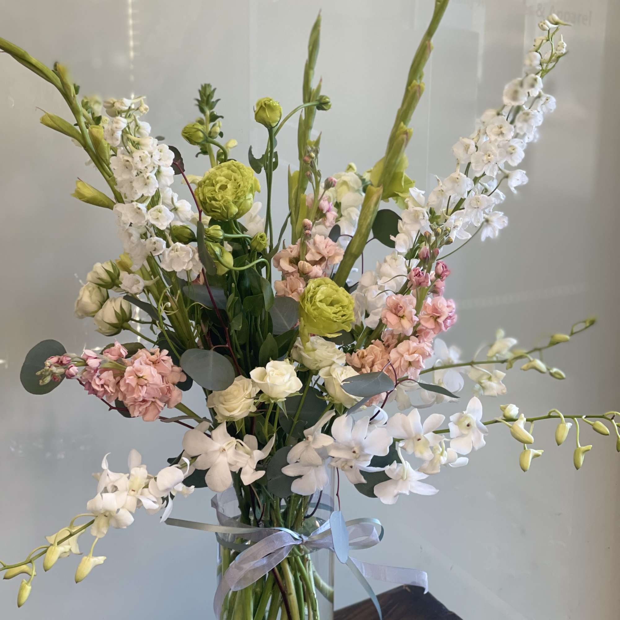Tall mixed bouquet in a clear glass vase with white, pink, and green blooms
