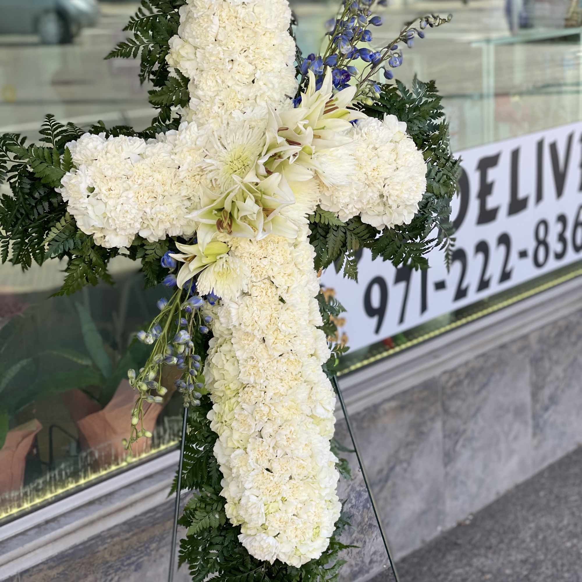 White floral cross on a stand with blue accents