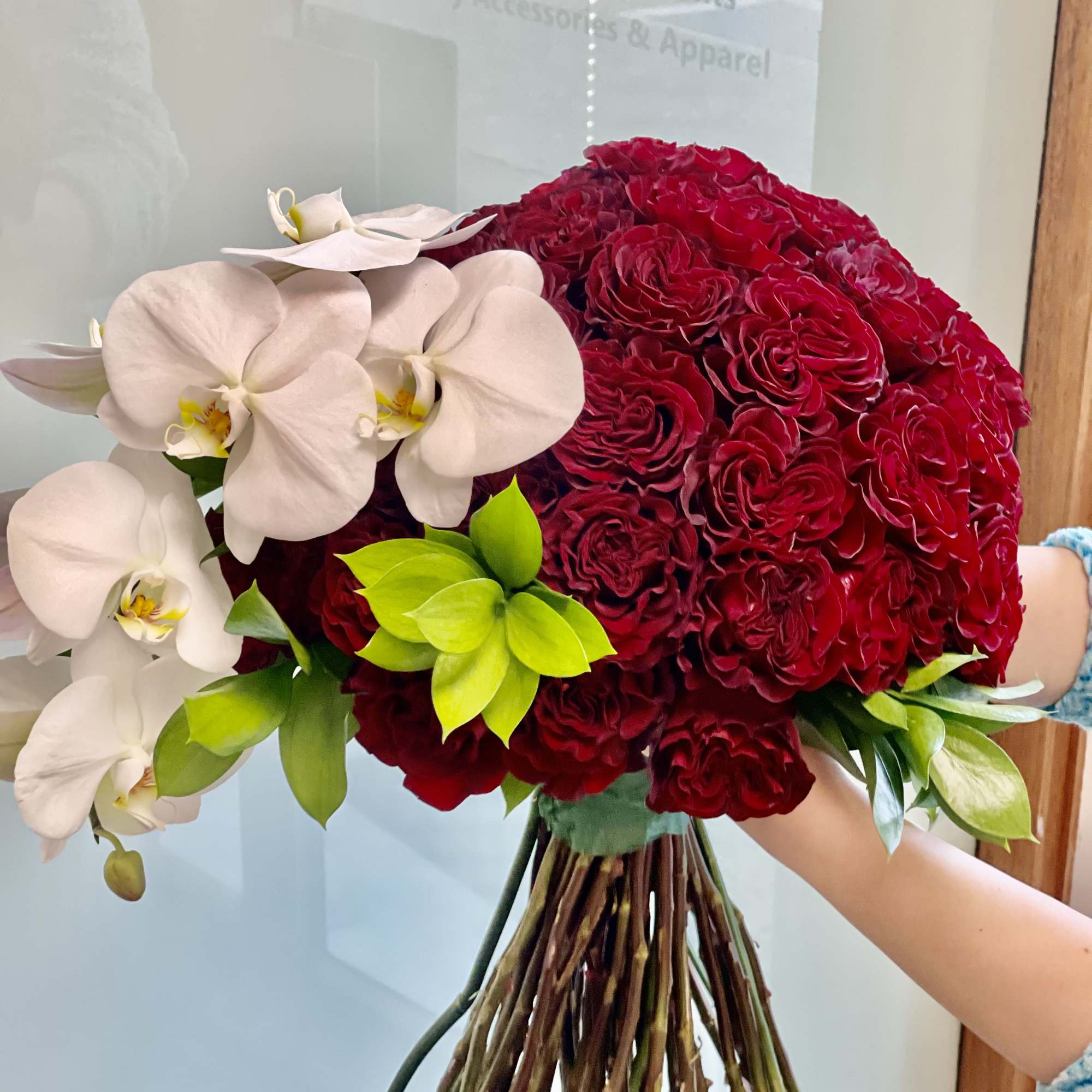 Bouquet of red roses and white orchids with bright green accents