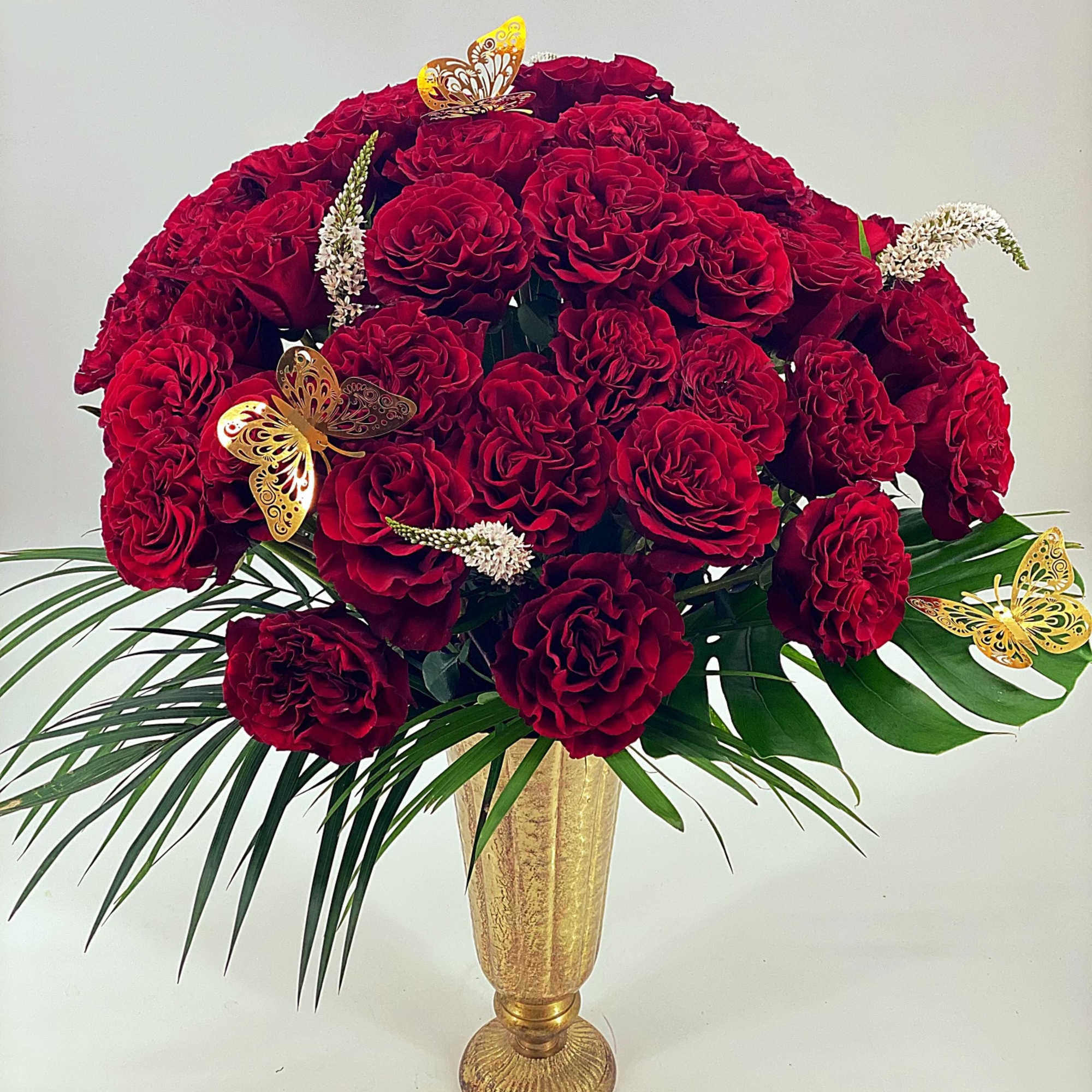 Large bouquet of red roses in a gold vase with butterfly accents