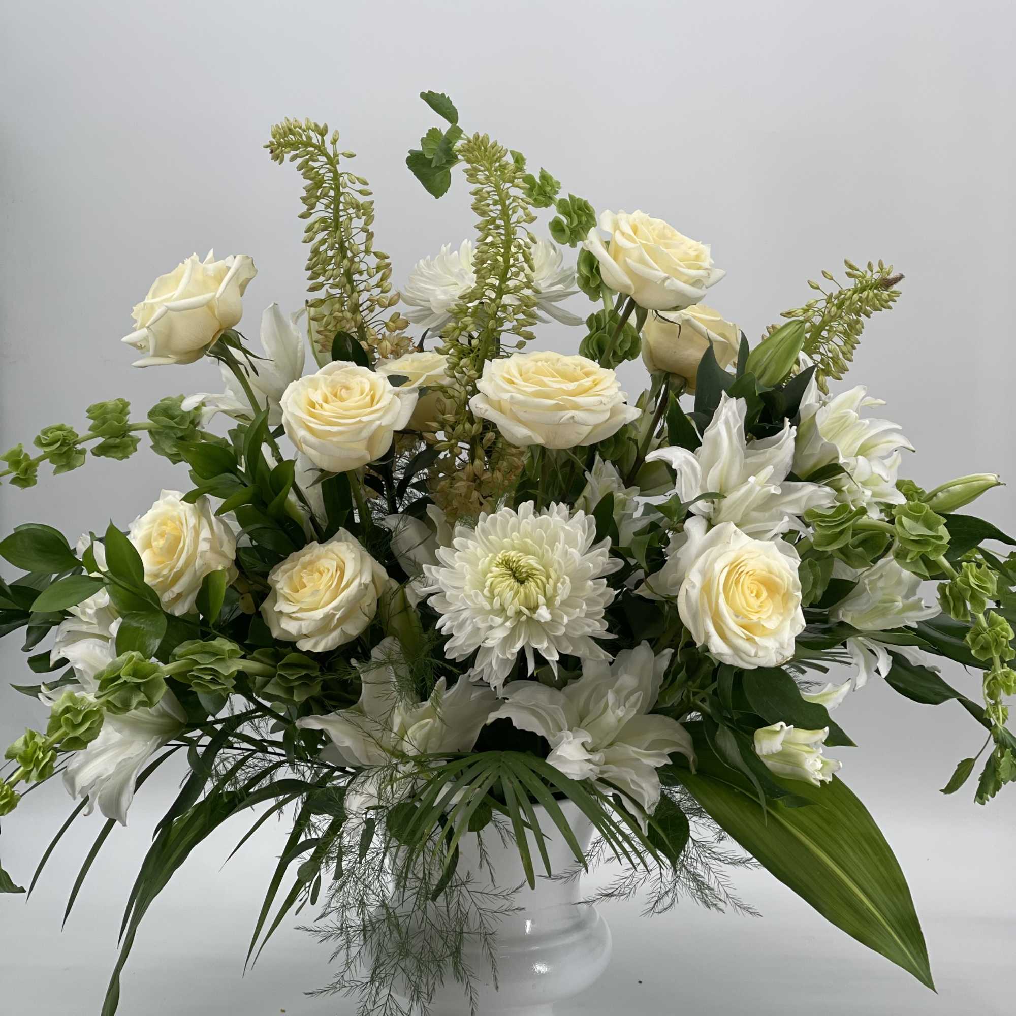 White roses and chrysanthemums in a white pedestal vase