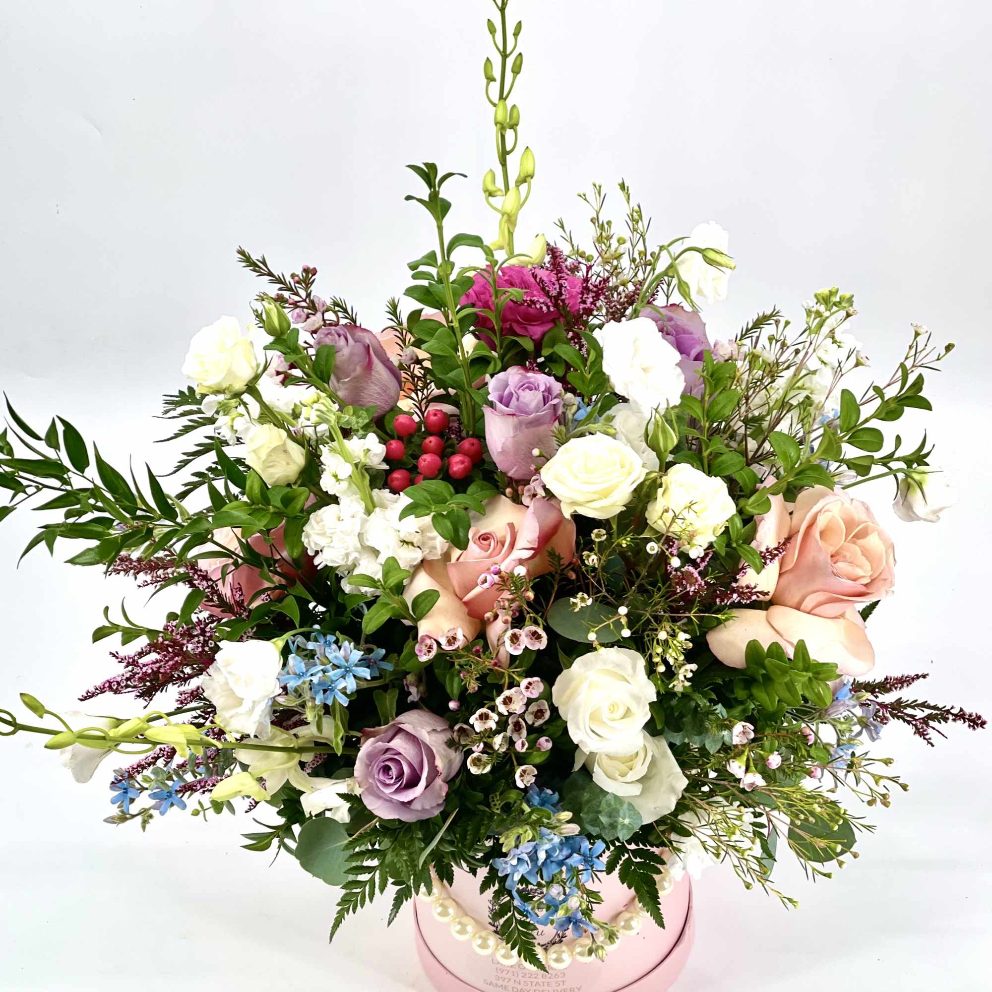 Mixed bouquet of roses and small accent flowers in a pink hatbox