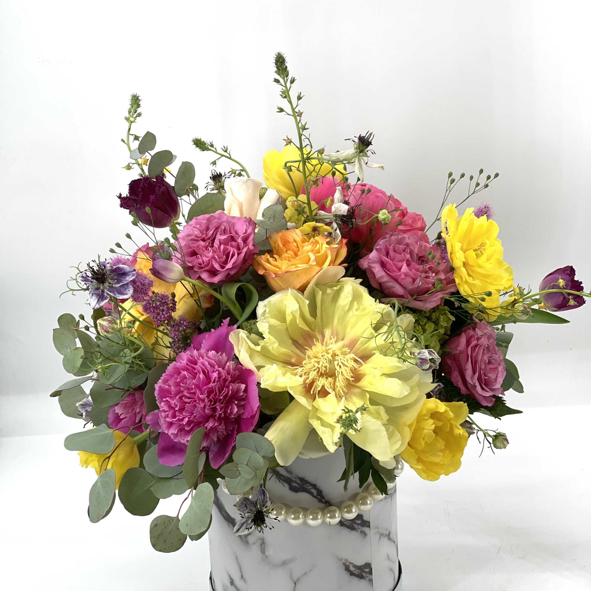 Colorful mixed flower arrangement in a marble-patterned round box
