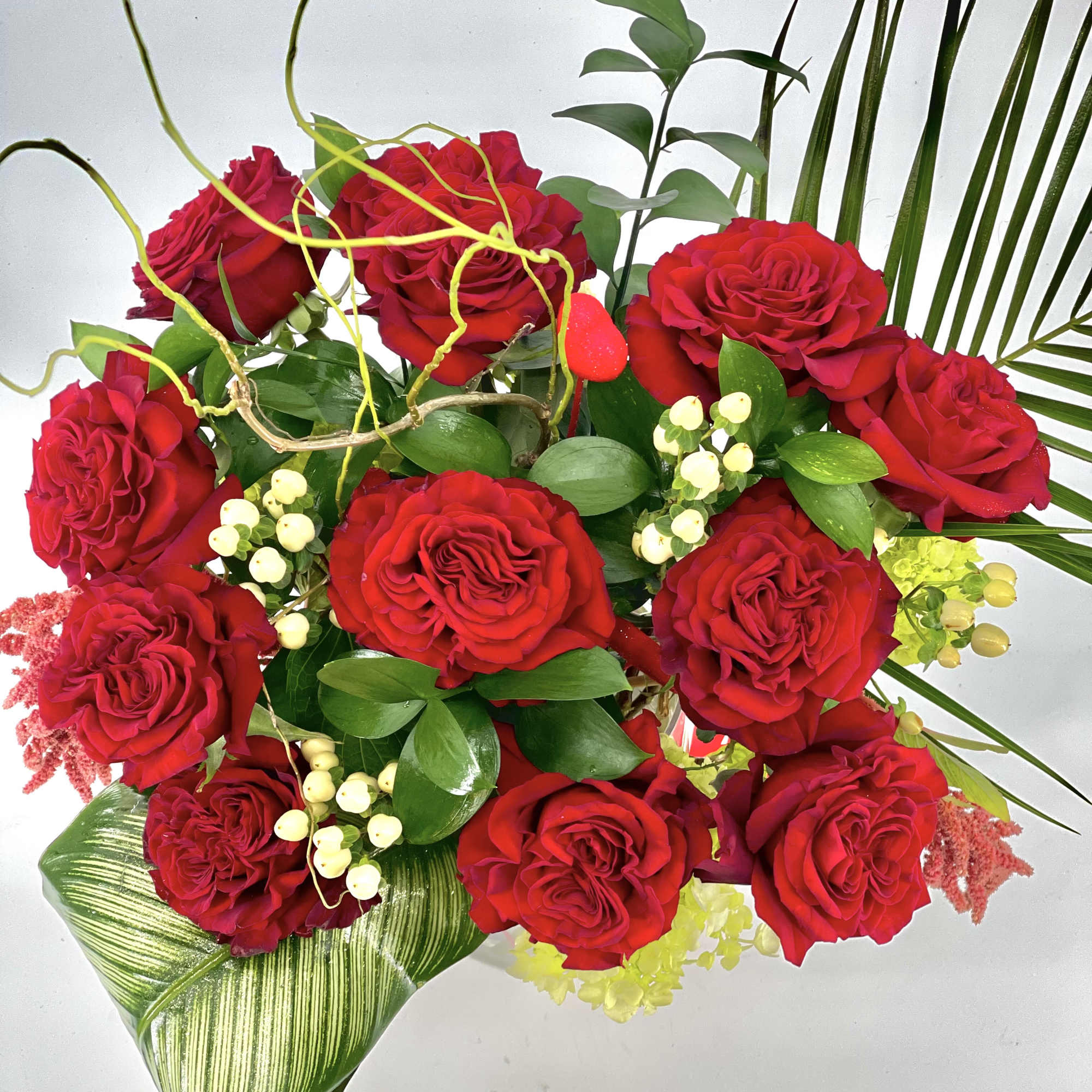 Bouquet of red roses with mixed greenery and white berry accents