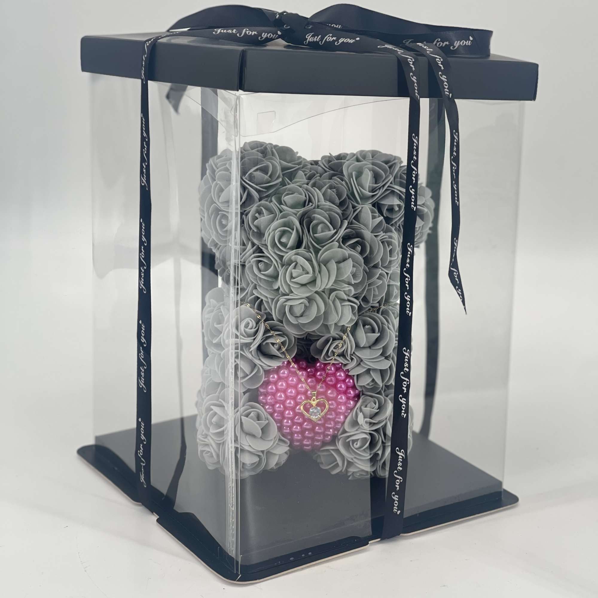 Gray rose-shaped arrangement in a clear gift box with a pink heart charm