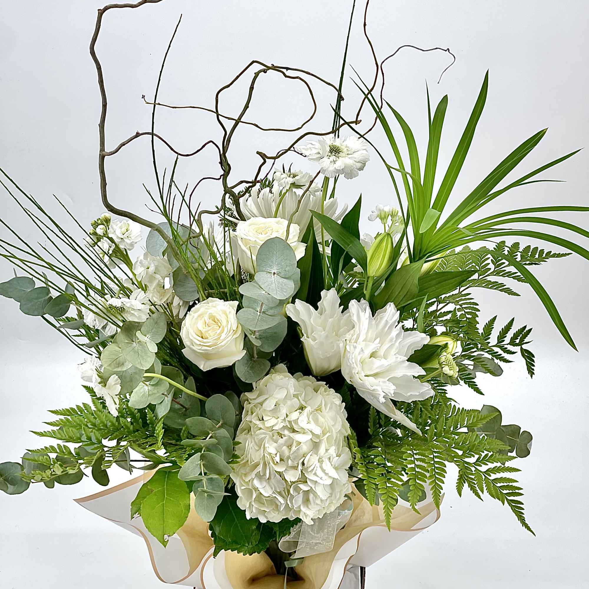 Tall white flower arrangement with roses, hydrangea, lilies and curly branches in a box container