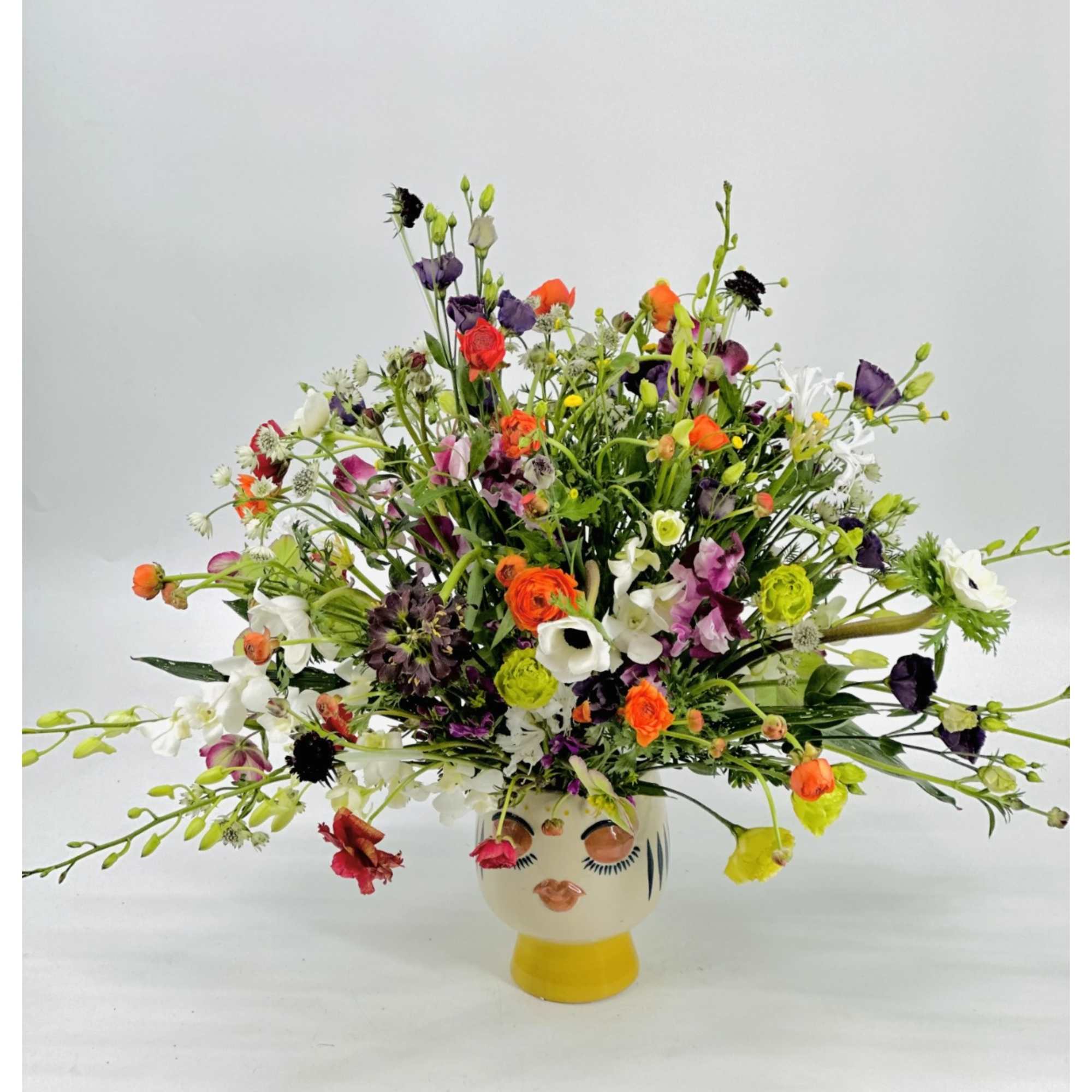 Colorful mixed flower arrangement in a decorative face vase
