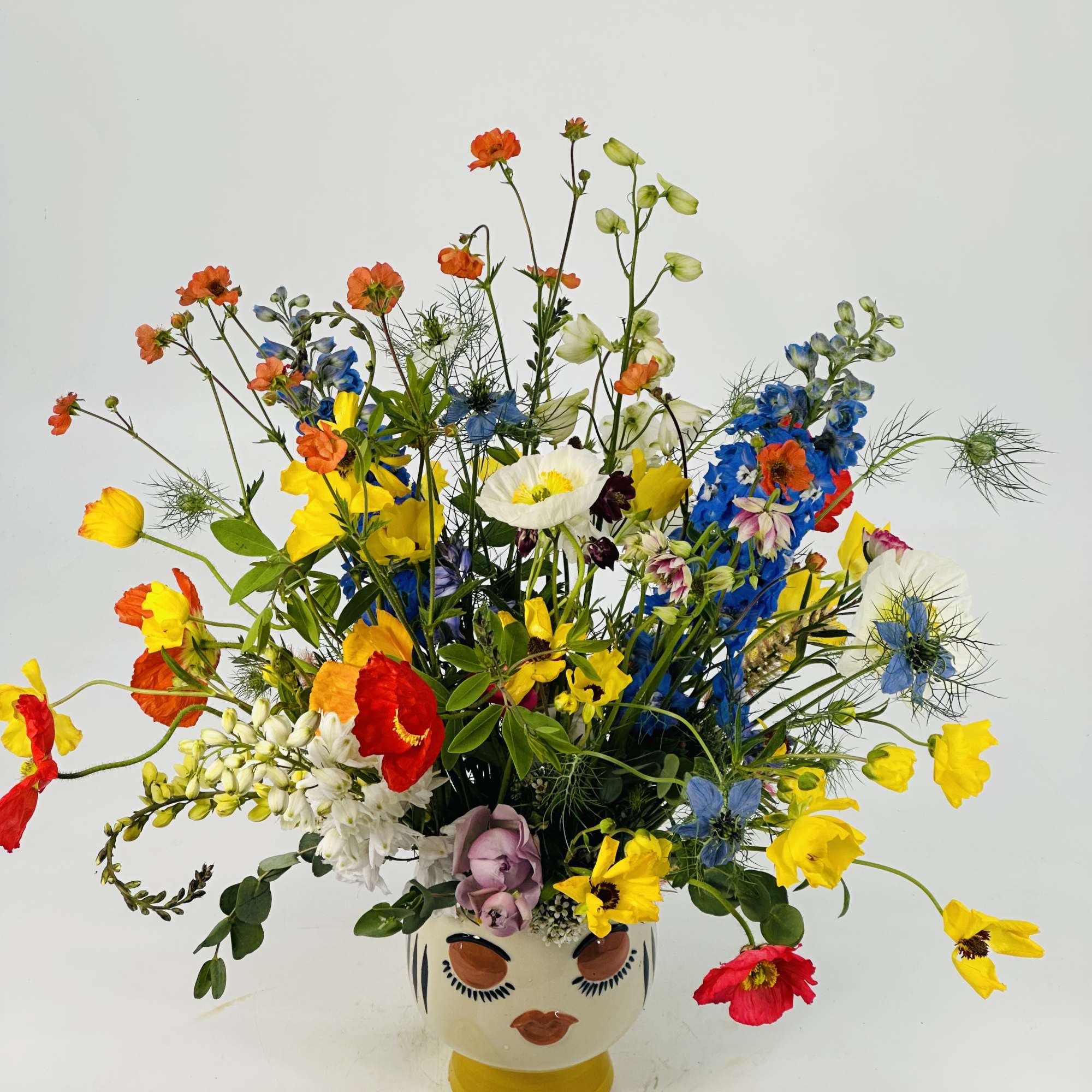 Colorful mixed flower arrangement in a painted face vase