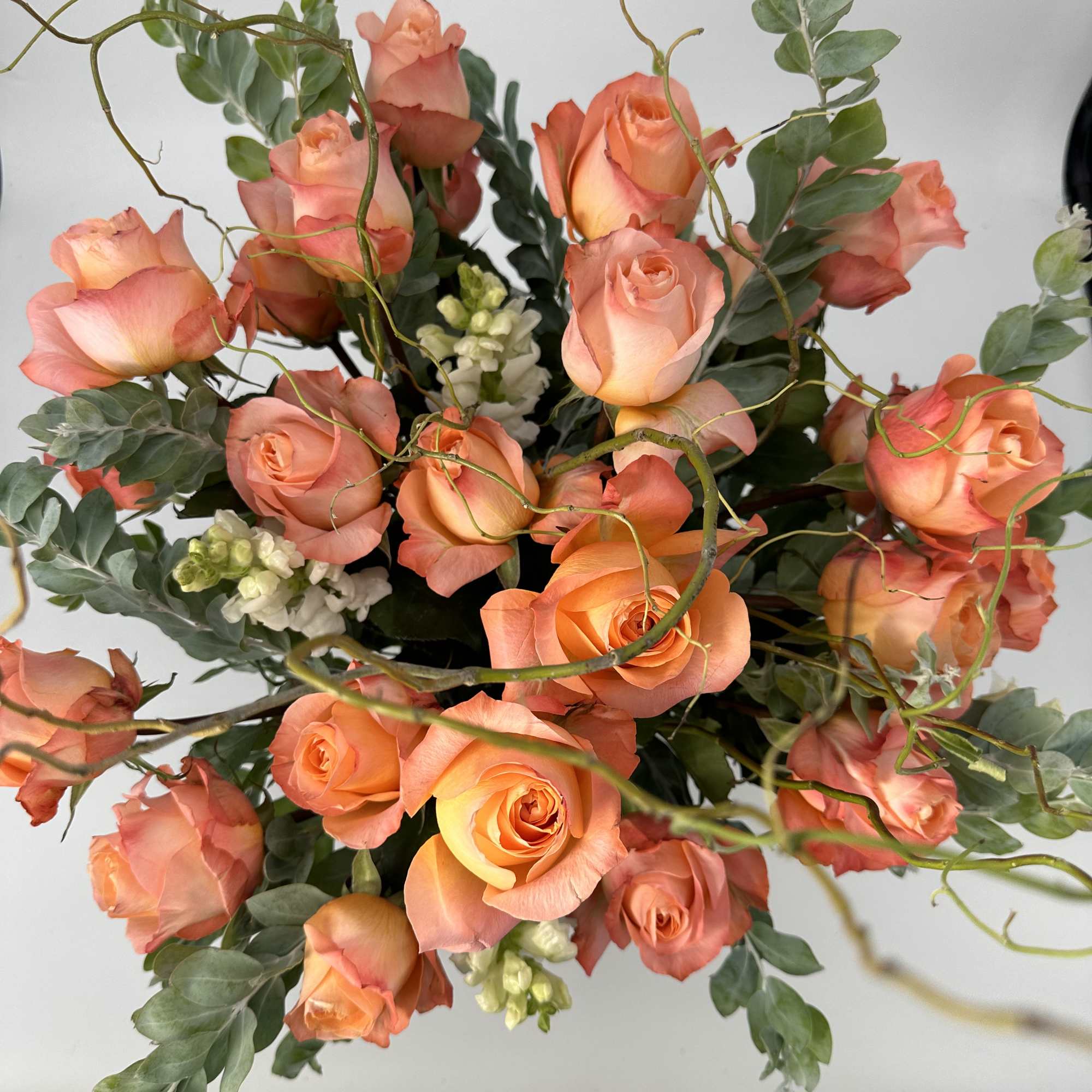 Bouquet of peach roses with greenery and white filler flowers