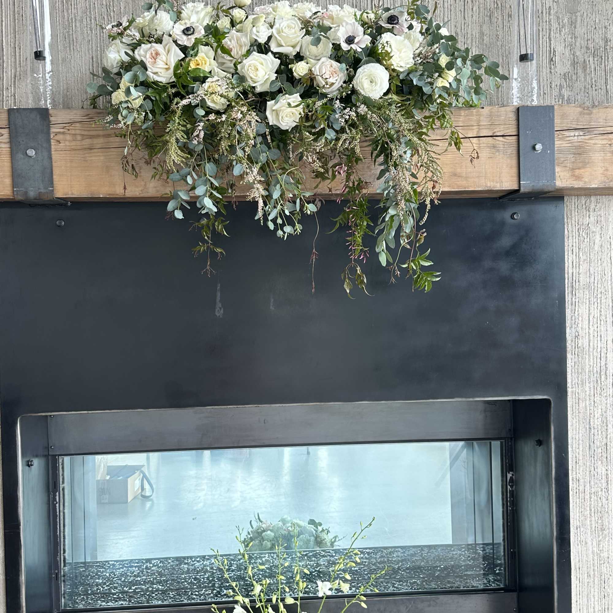 White floral arrangement with trailing greenery on a mantel above a fireplace