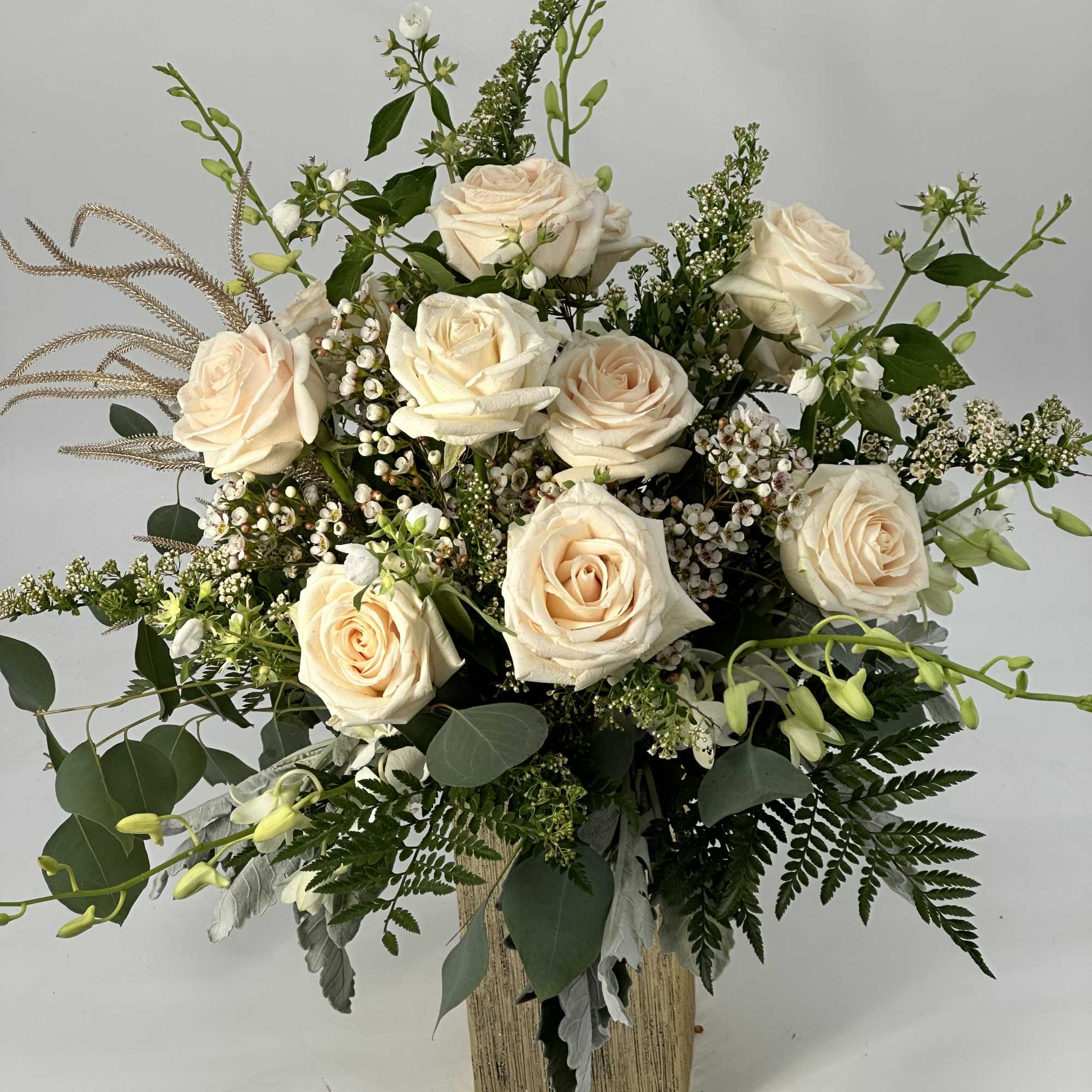 Cream rose arrangement in a square vase with mixed greenery