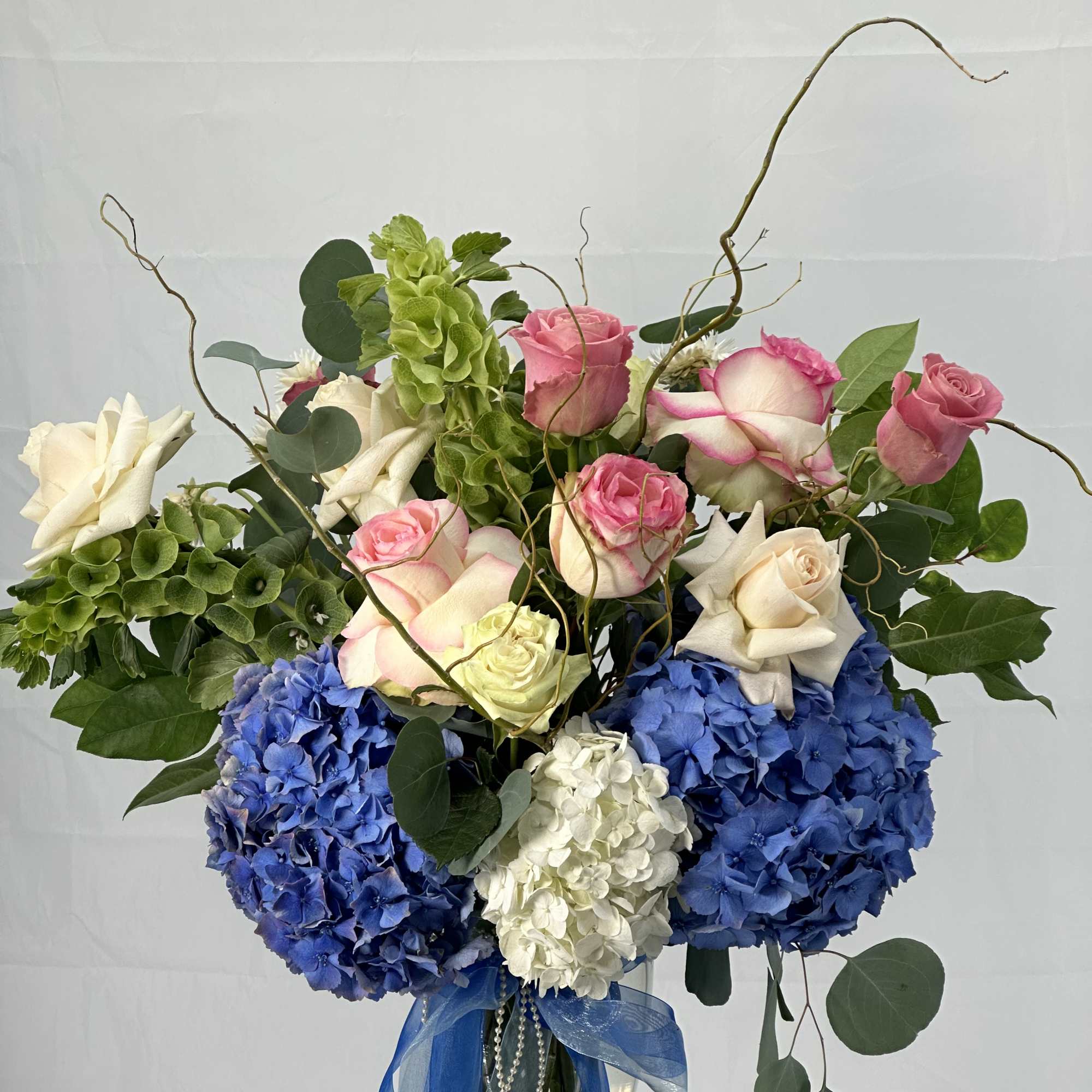 Bouquet of pink and white roses with blue hydrangeas in a glass vase