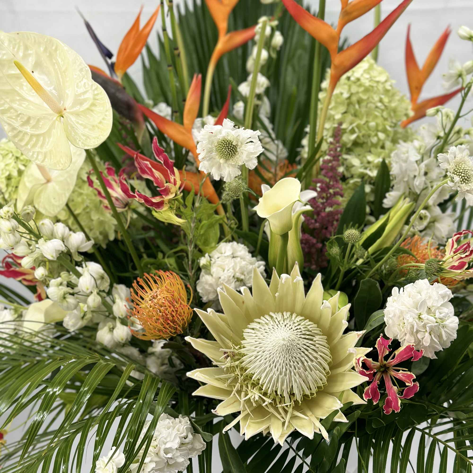 Tropical floral arrangement with orange heliconia and white blooms