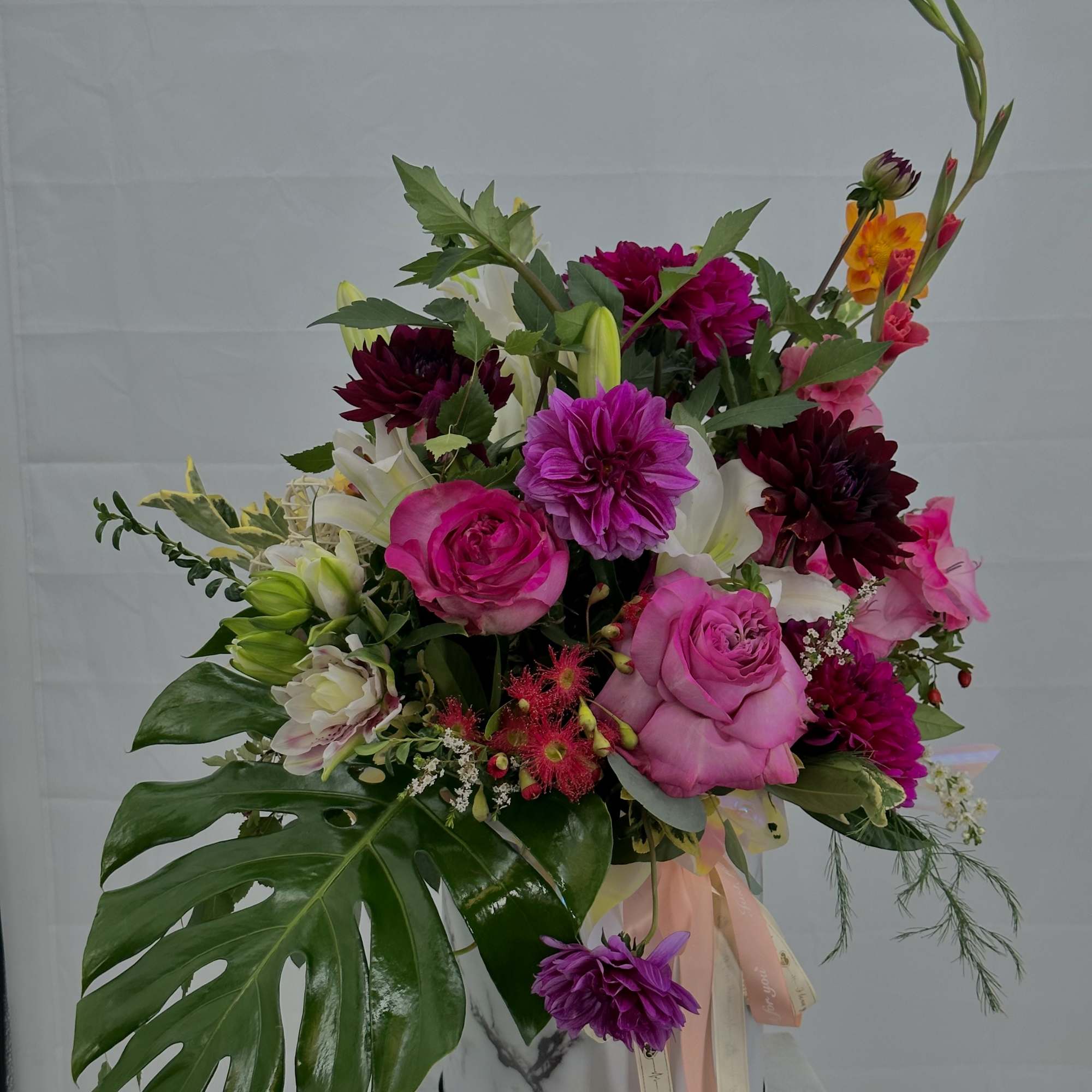 Mixed bouquet of pink and white flowers in a marble-patterned container
