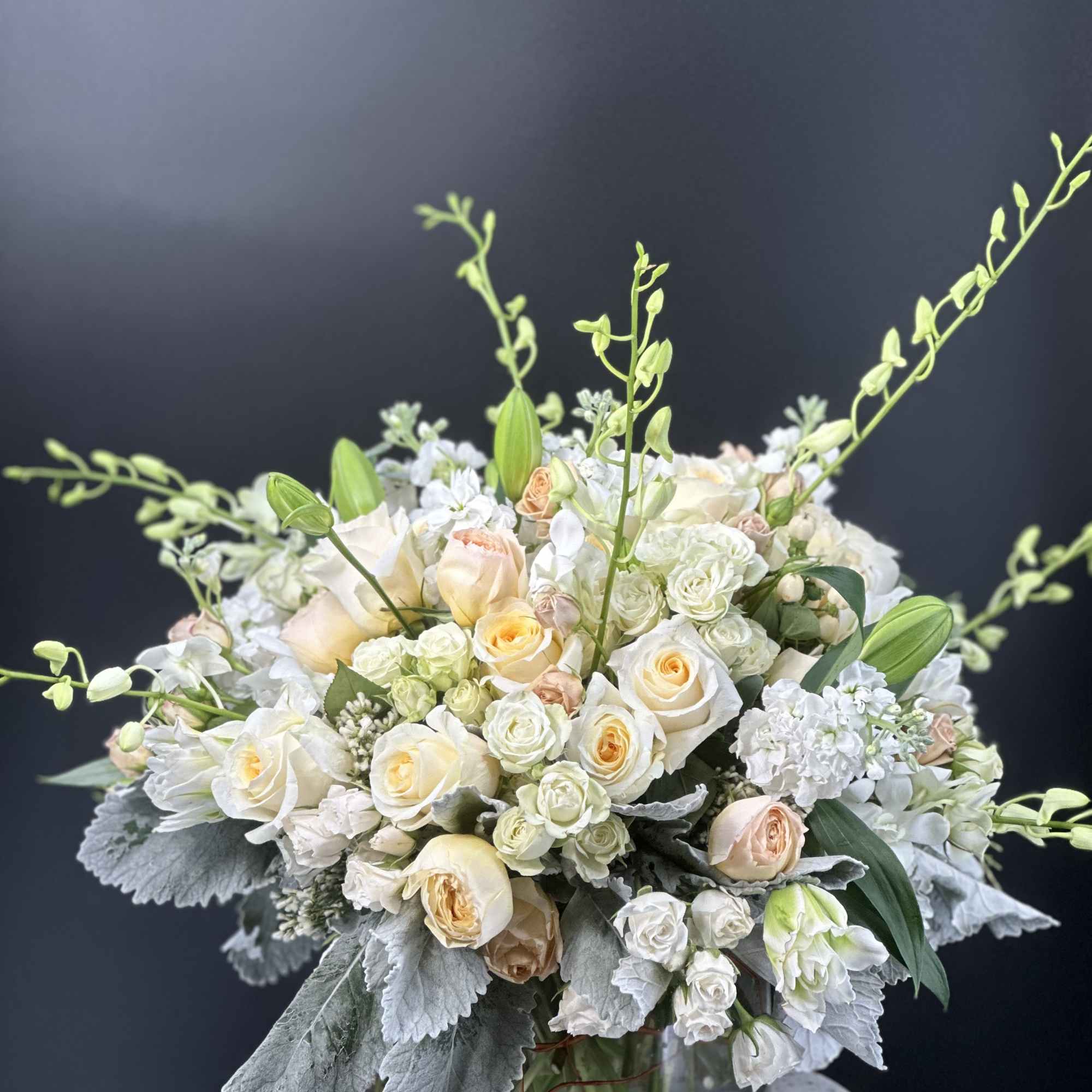 Cream and blush rose bouquet in a glass vase with tall green stems