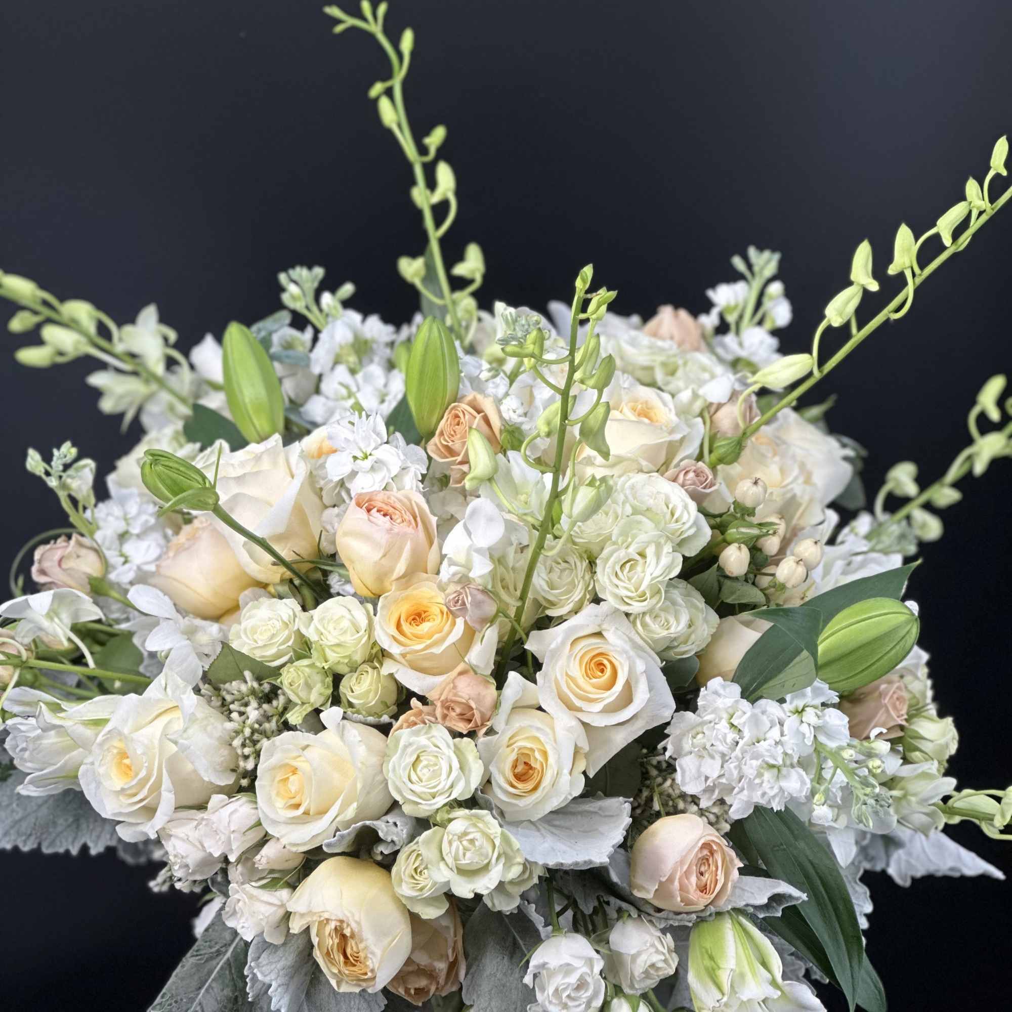 Cream and peach rose bouquet with white blooms in a glass vase
