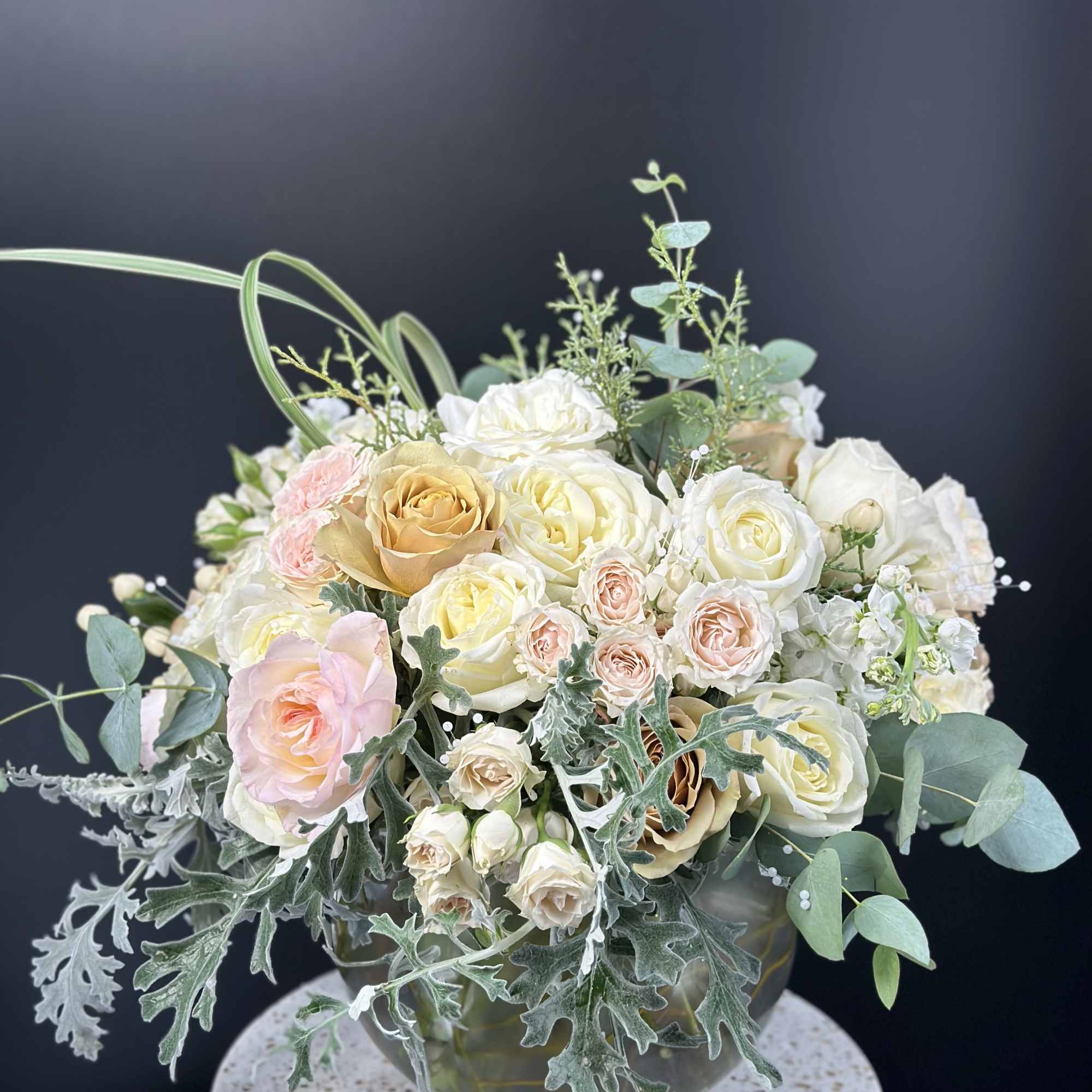 Bouquet of cream and blush roses in a glass vase