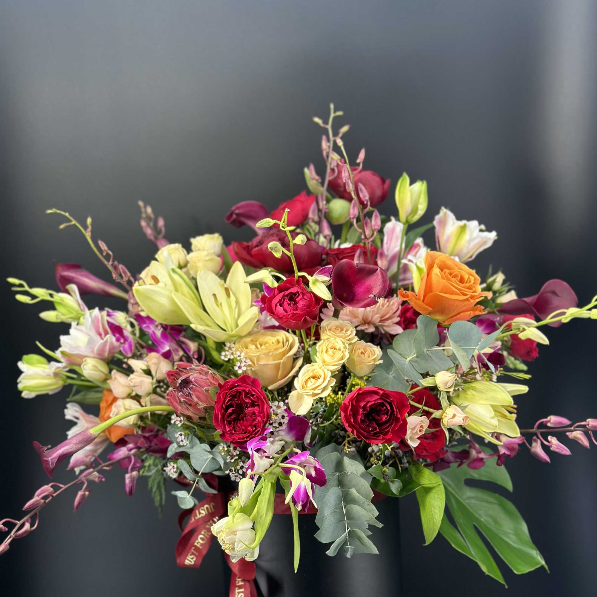 Mixed bouquet in a black hat box with roses and lilies