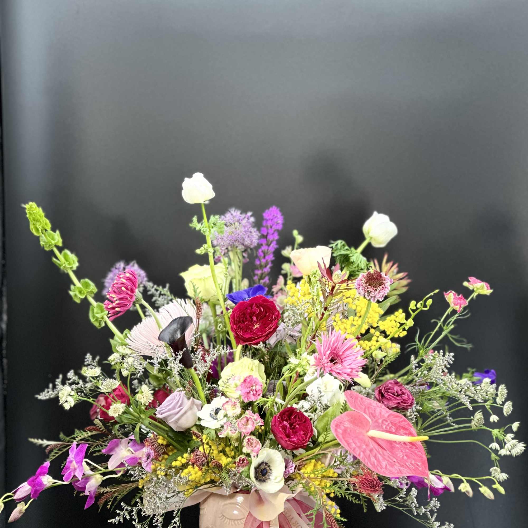 Colorful mixed bouquet in a pink vase with a ribbon