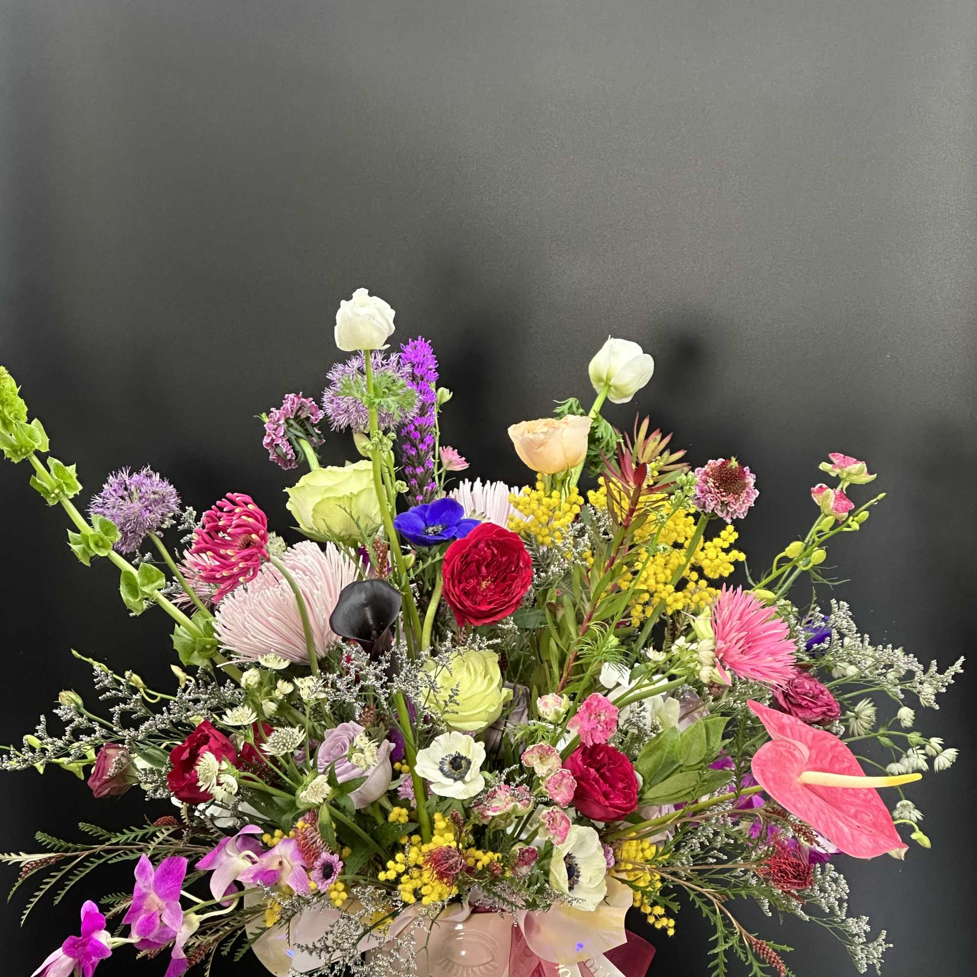 Colorful mixed bouquet in a pink vase with ribbon