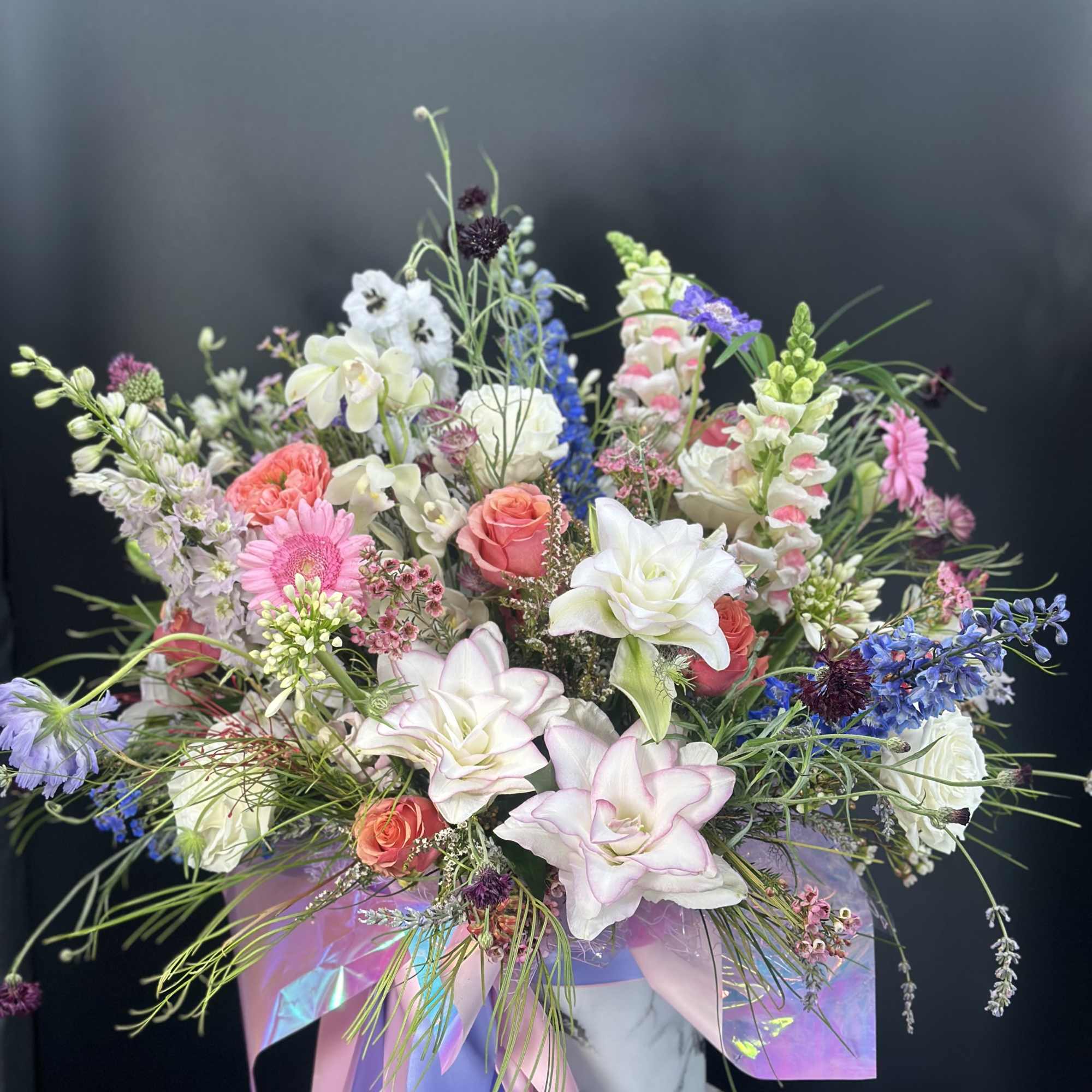 Mixed bouquet with pink, white, and blue flowers in a marble vase