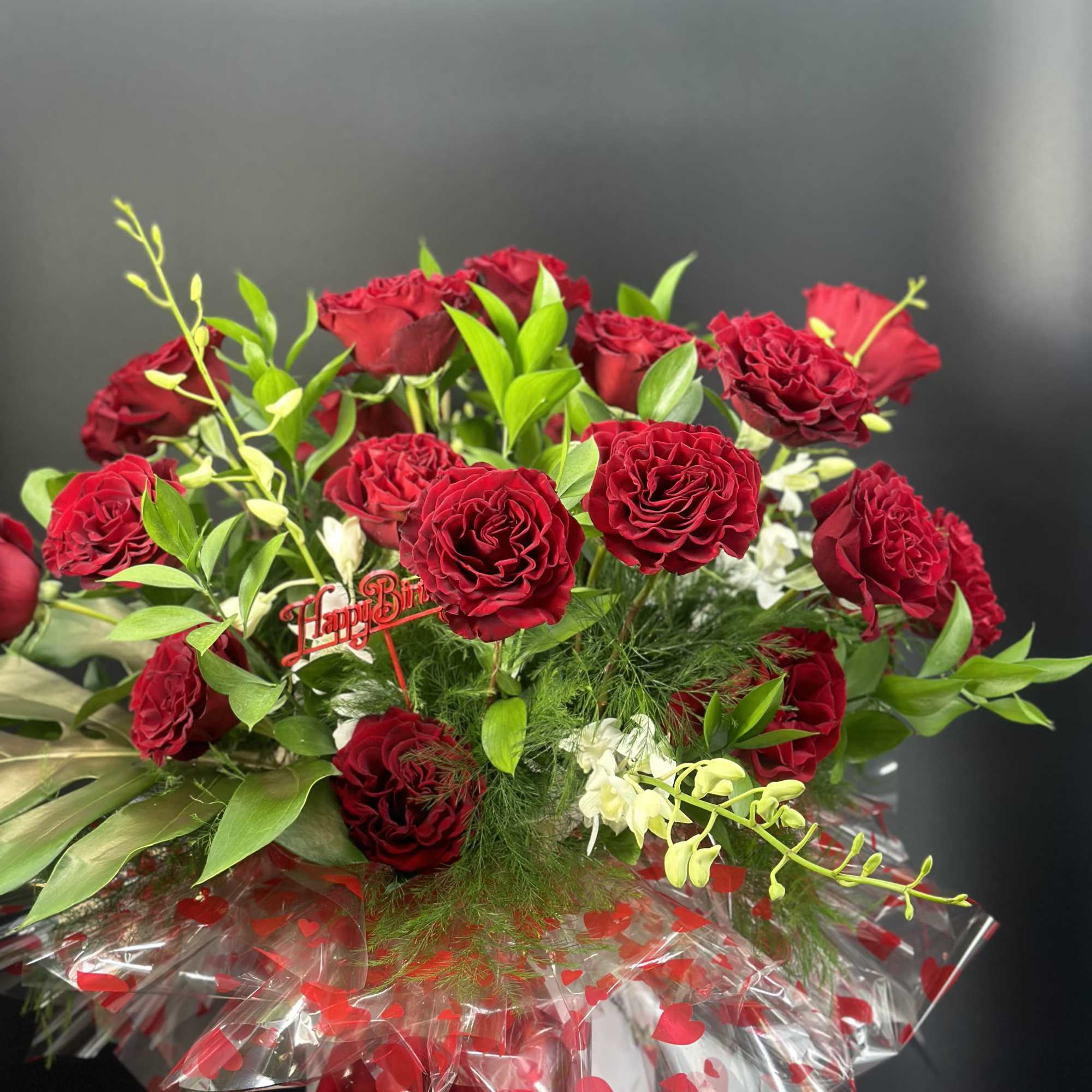 Bouquet of red roses with white orchids and a red ribbon in a vase