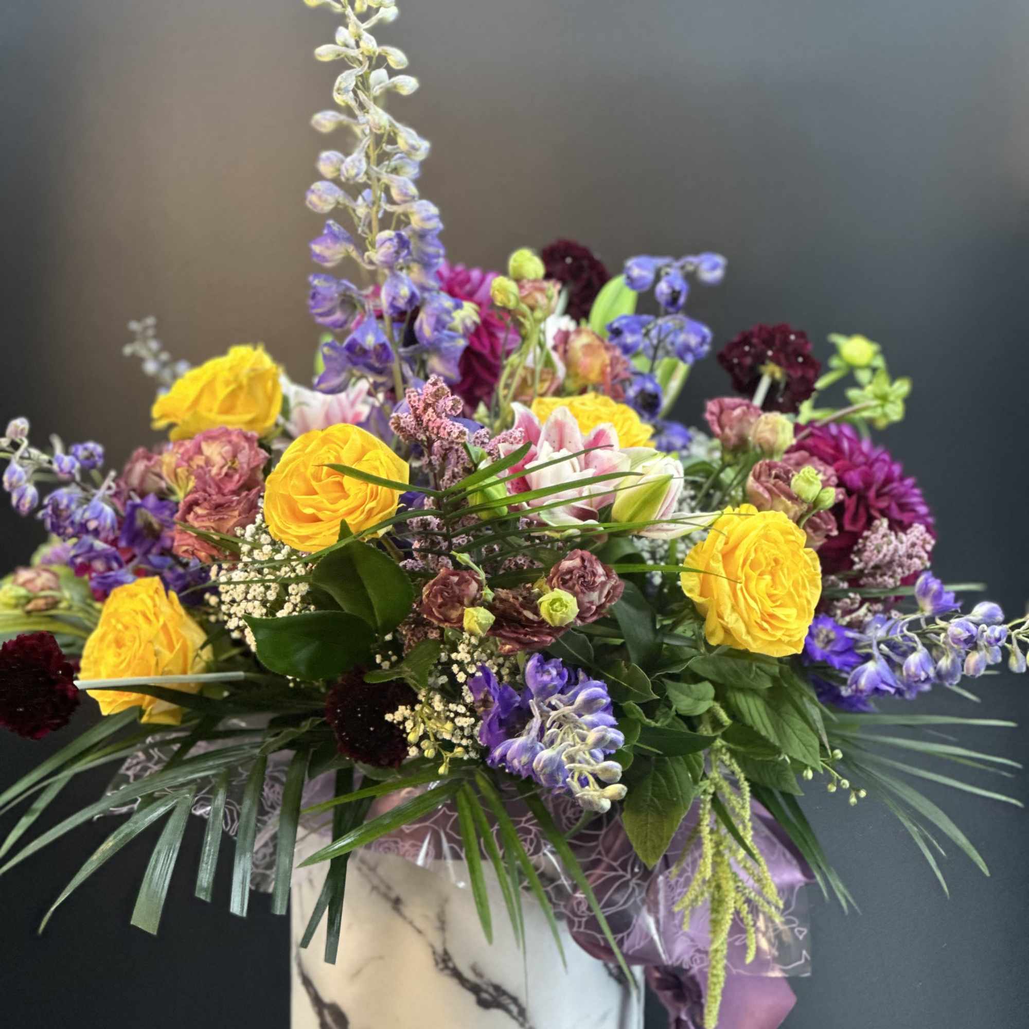 Mixed bouquet in a marble-patterned box with yellow and purple flowers