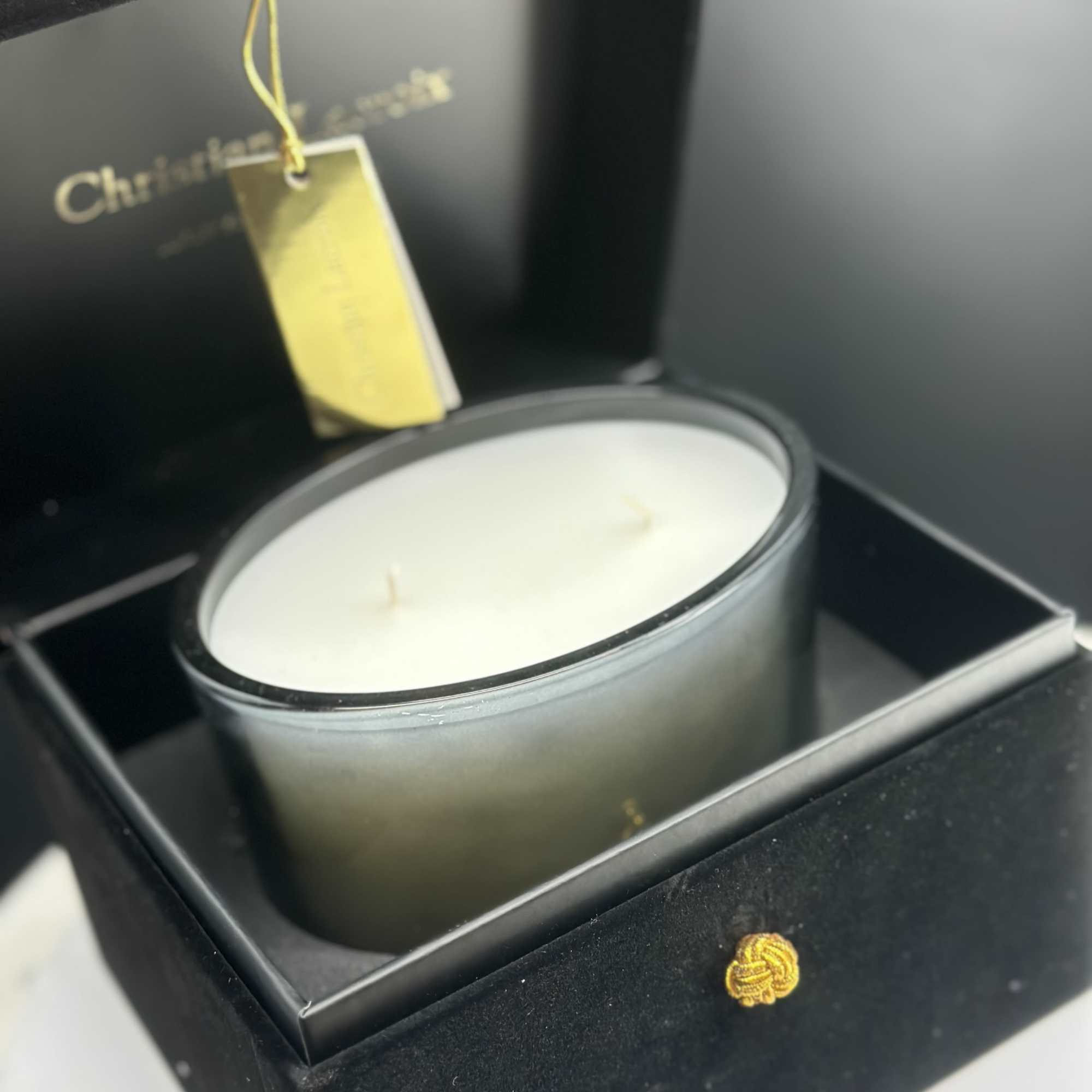 White candle in a black gift box with a hanging tag