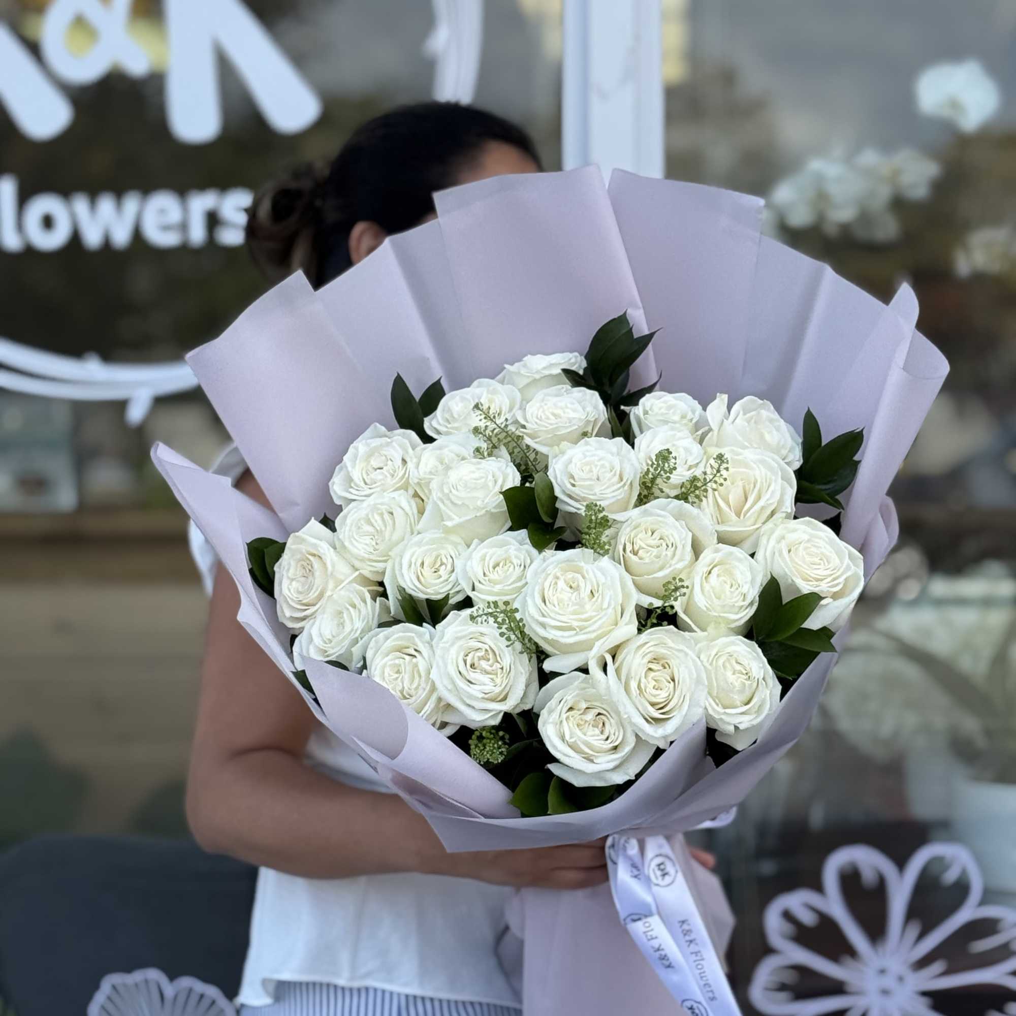 Bouquet of white roses wrapped in pale lavender paper