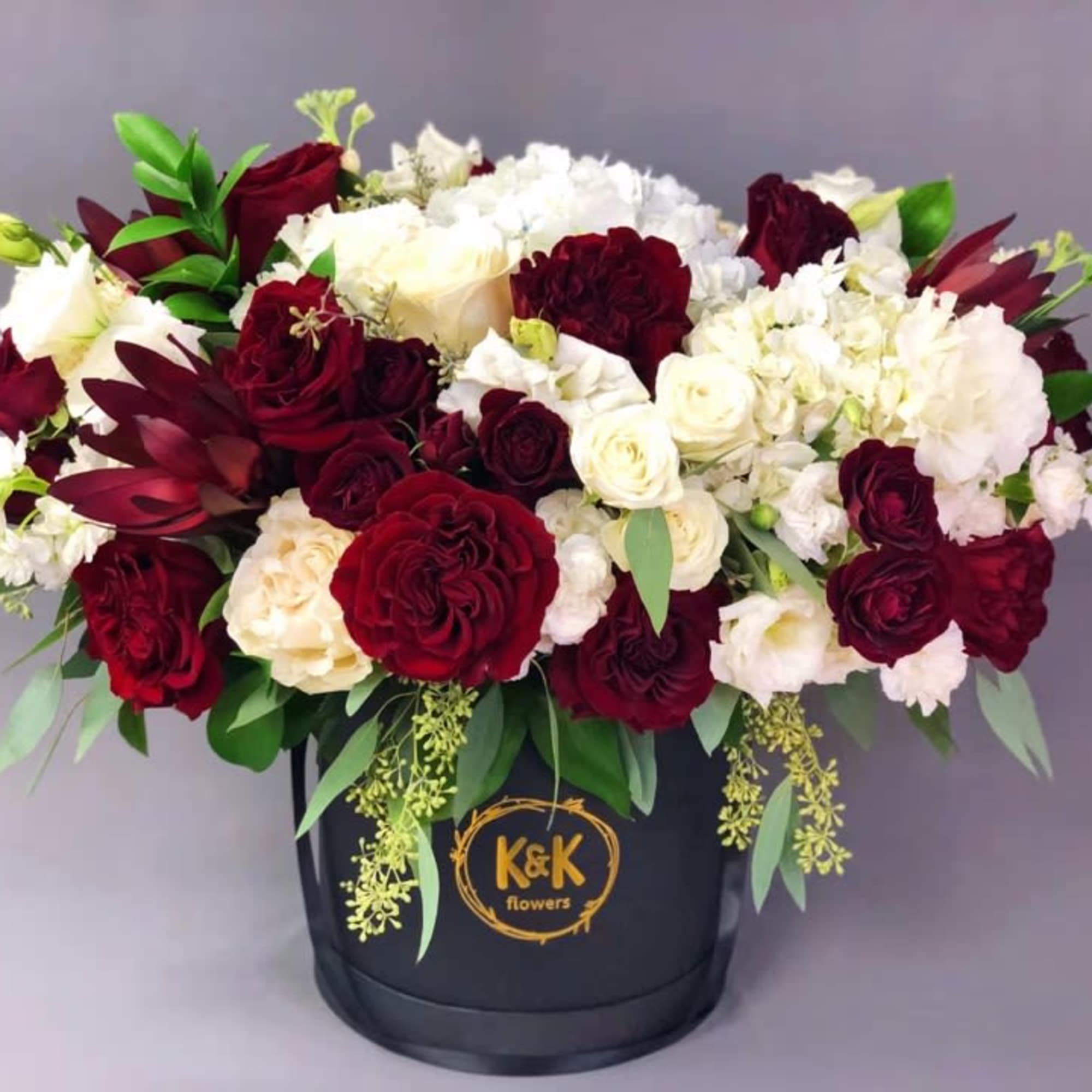 Red and white roses arranged in a black hatbox