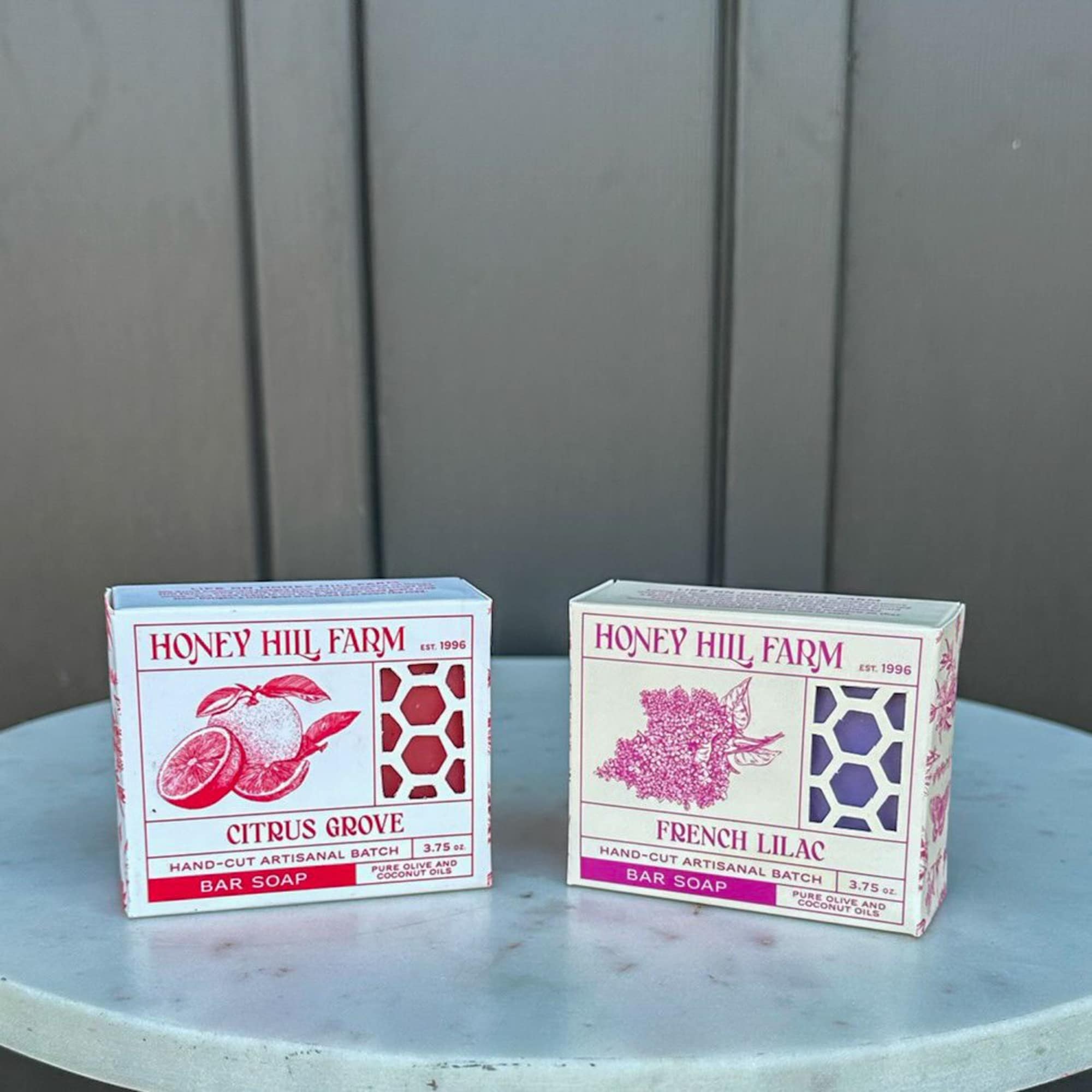 Two boxed bar soaps on a small round marble table against a dark wall.